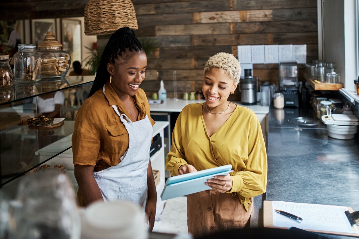 Two women working with a tablet in a coffee shop to market their restaurant - SkyTab - Shift4