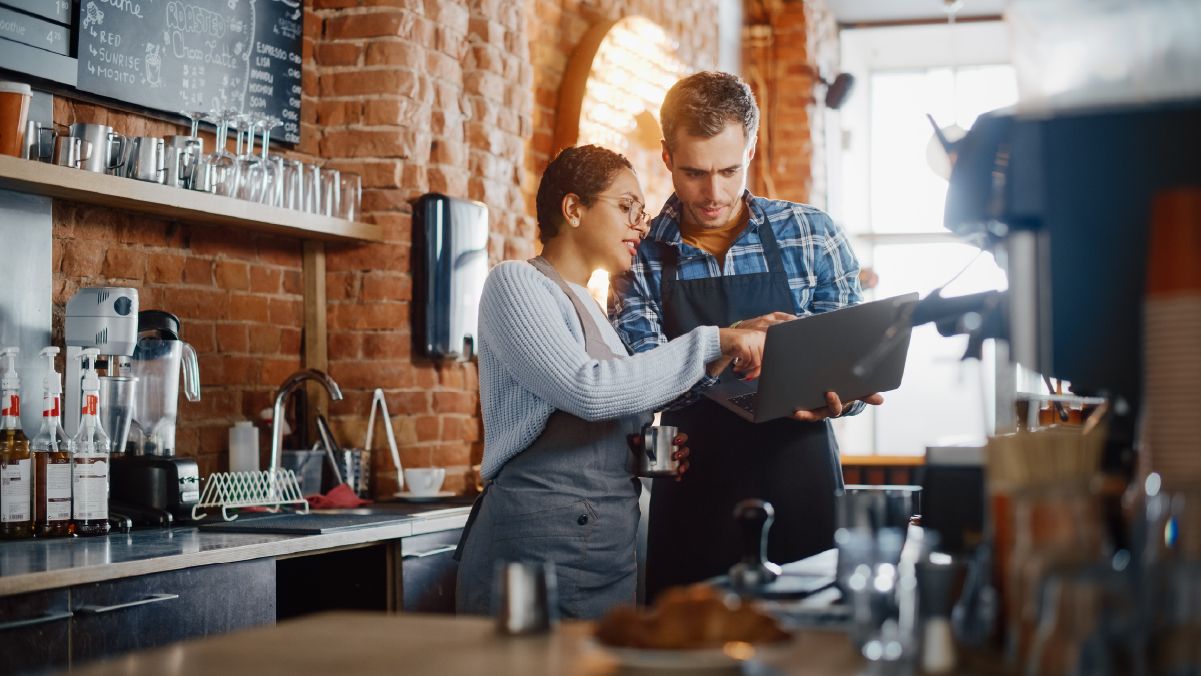 Two employees looking at a restaurant profit and loss statement on a laptop - SkyTab - Shift4