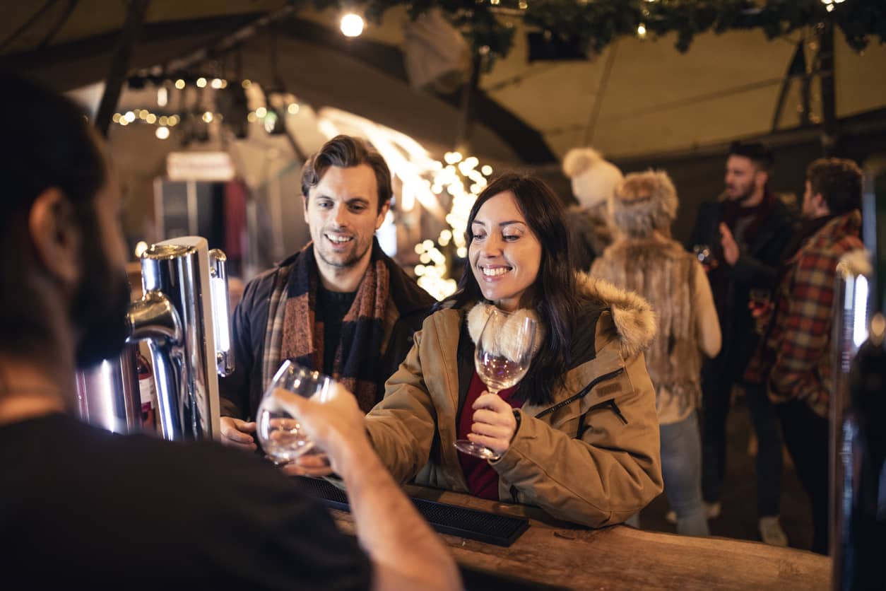 Two customers ordering drinks at a restaurant bar during the holiday season - SkyTab - Shift4