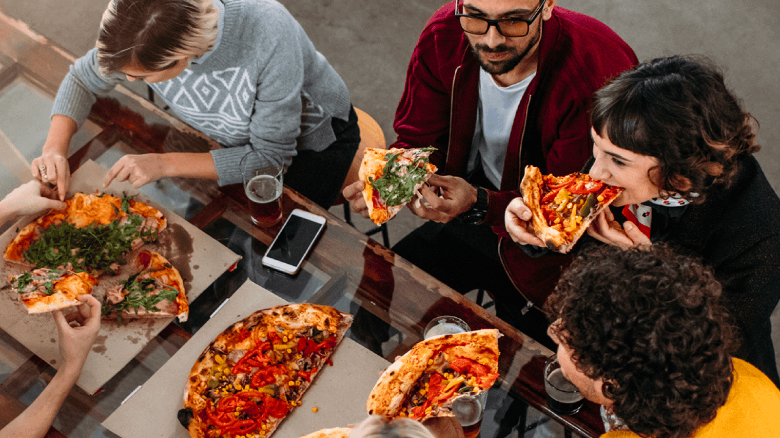 Five people eating pizza at a table in a pizzeria