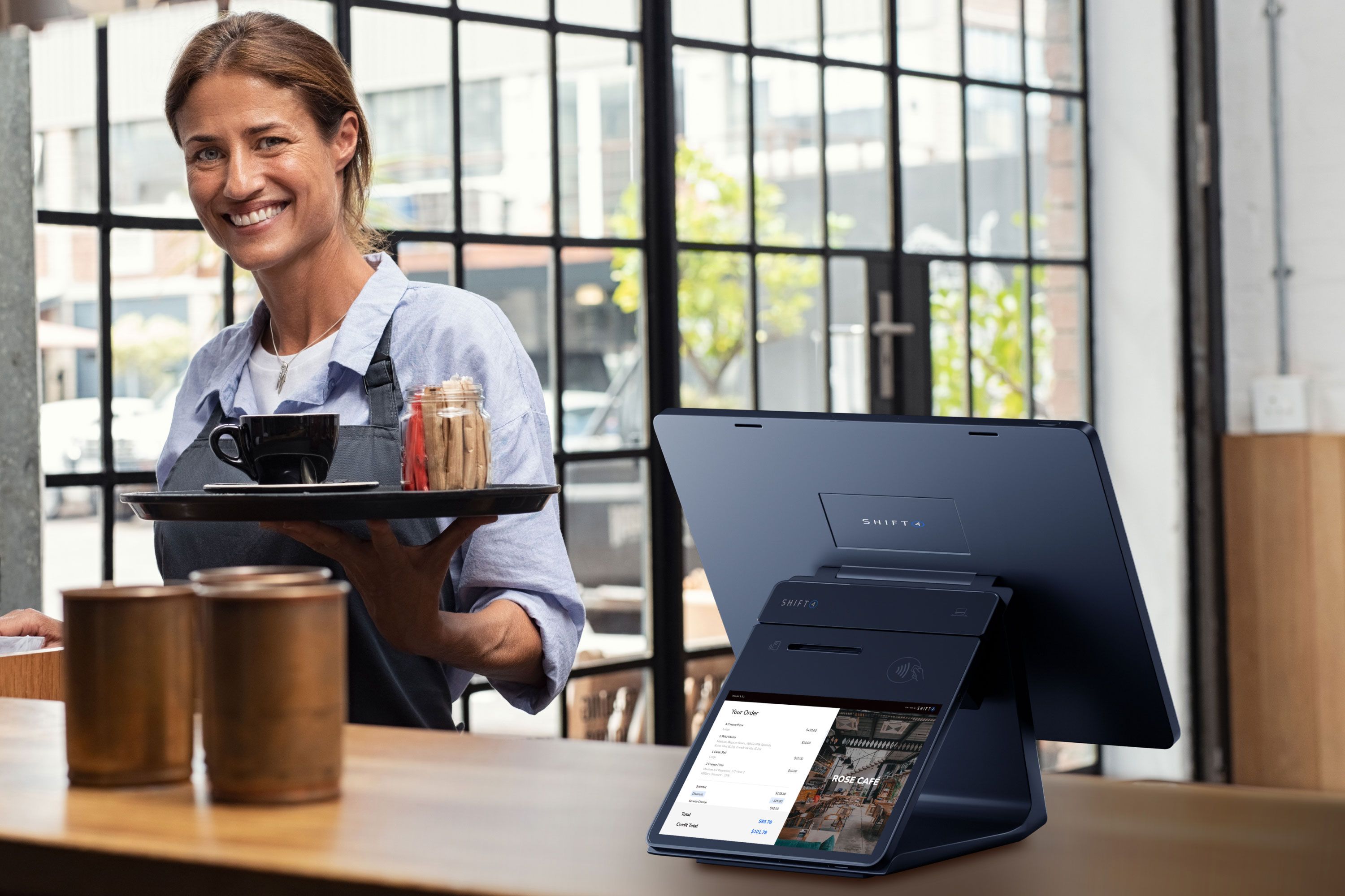 A restaurant employee standing next to a SkyTab POS system with a customer-facing display