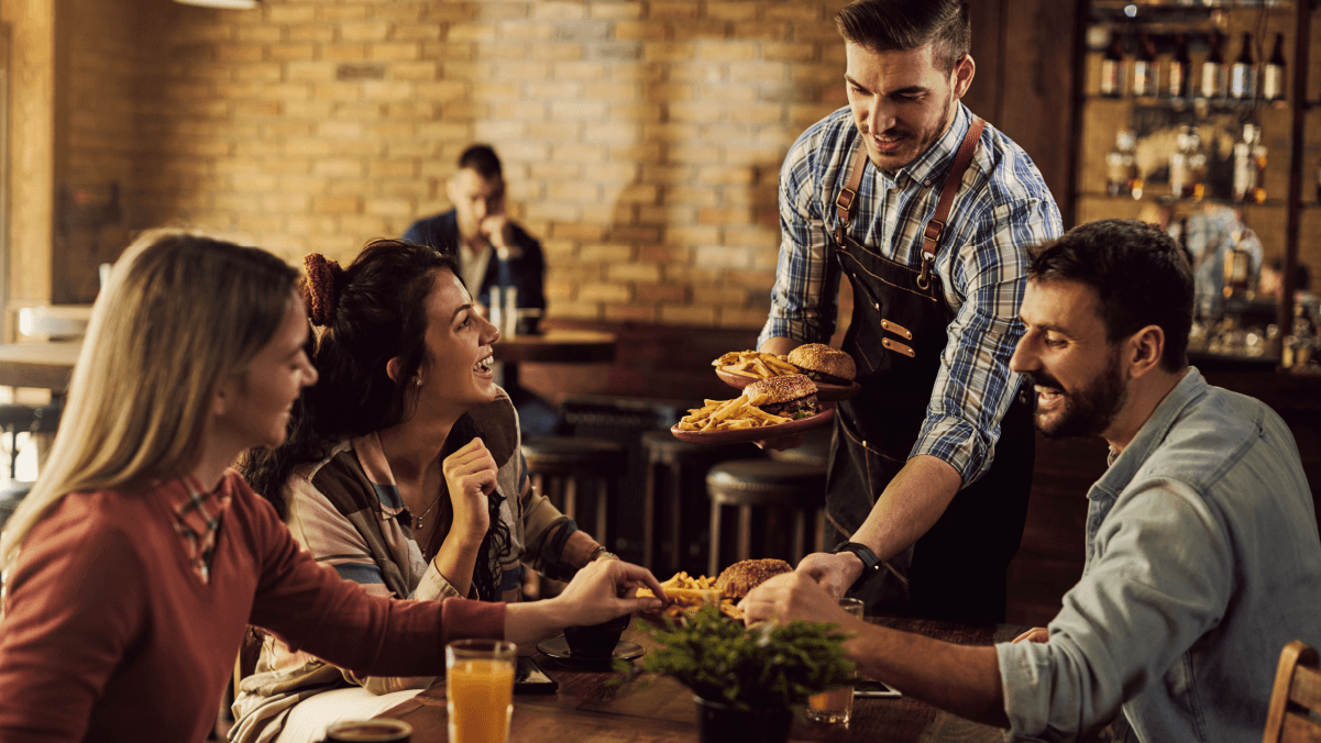 Three diners receiving their order in a restaurant from a waiter | SkyTab