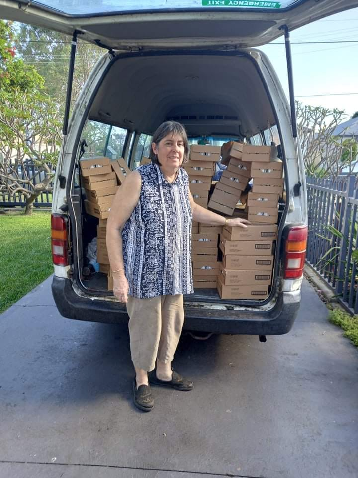 woman standing in front of a car full of boxes 