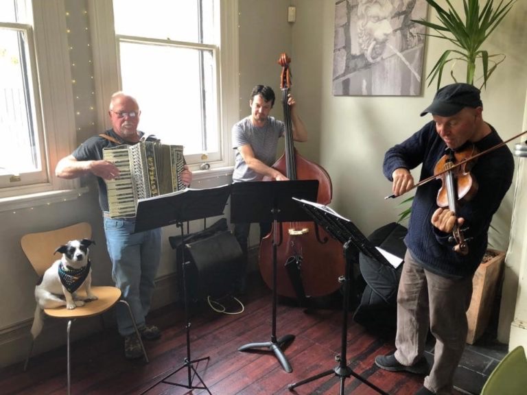 Bruce plays with his band, with Chloe sitting on a chair 