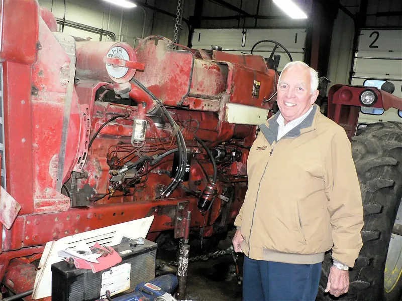 Ken Statz beside a Farmall tractor during repairs, 2018.