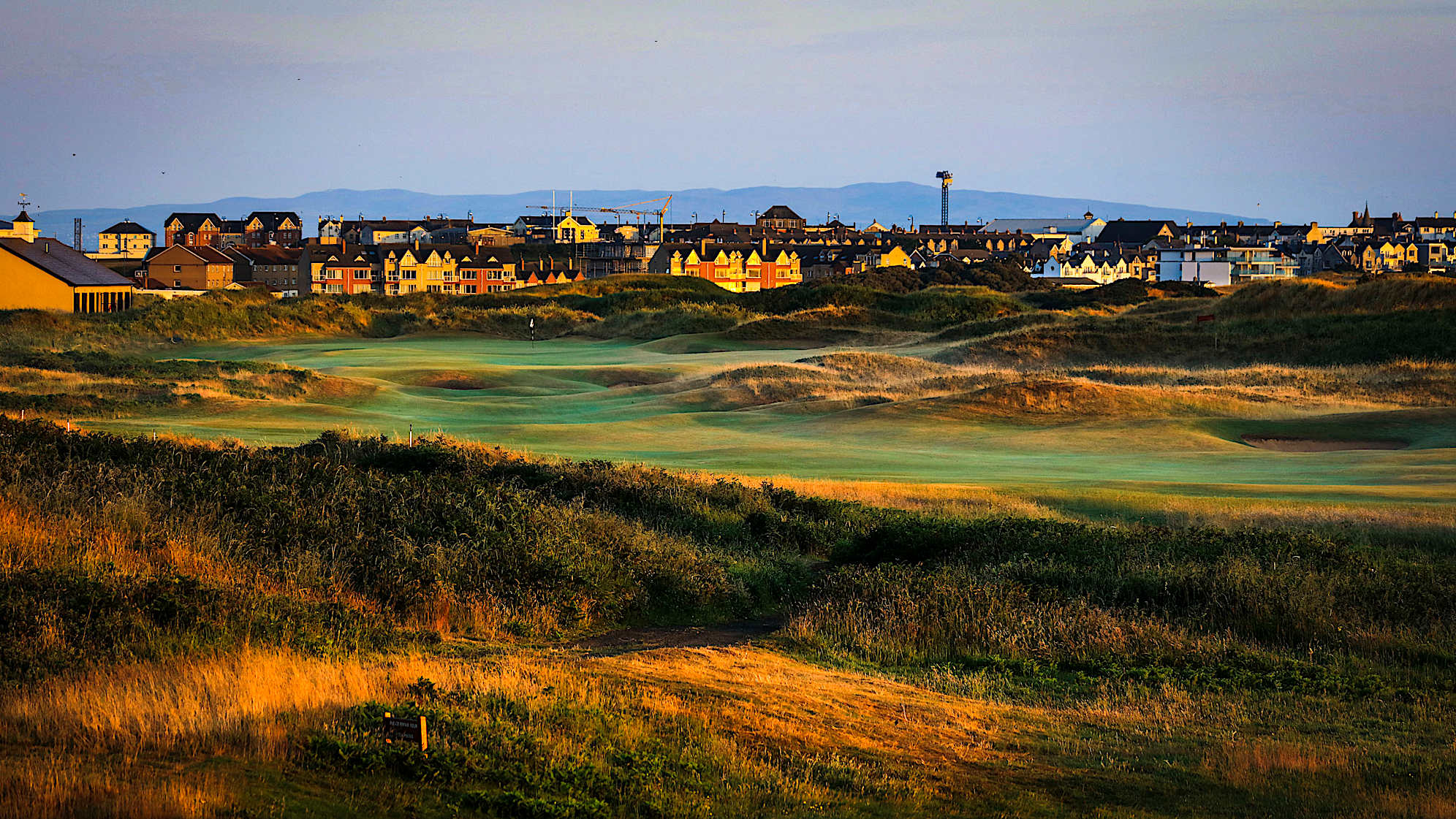 BABINGTON'S: For the closing hole, a new tee means driver will be in the player’s mind to position the ball down into the left portion of the fairway and provide a view of the green for the second shot. The green sits slightly sideways with a drop-off to the left that will collect any balls missing on that side. A strong finishing hole where the wind will be a determining factor in its difficulty through the Championship. In 1951 Max Faulkner famously played a miraculous shot from against the out of bounds fence down the left on his way to winning The Open. (Descriptions courtesy of the R&A)
