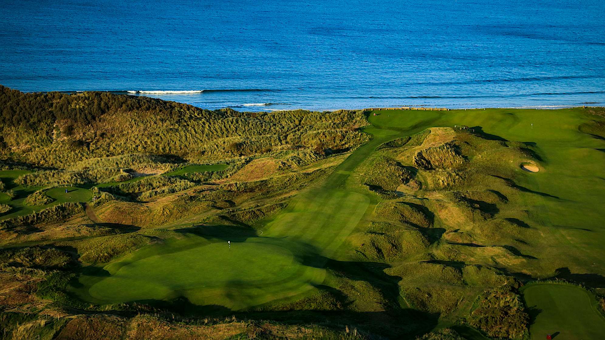 HARRY COLT'S: No. 6 is the second of the par-3s and another spectacular viewing hole for spectators. With no bunkers around the green, the sixth hole is well defended by the natural undulations of its surrounds. Named after Harry Colt, who designed the Dunluce layout in the 1930s, the elevated green has a false front that will punish anything short. Players will be satisfied with a par here before moving on to a tough stretch of holes. (Descriptions courtesy of the R&A)