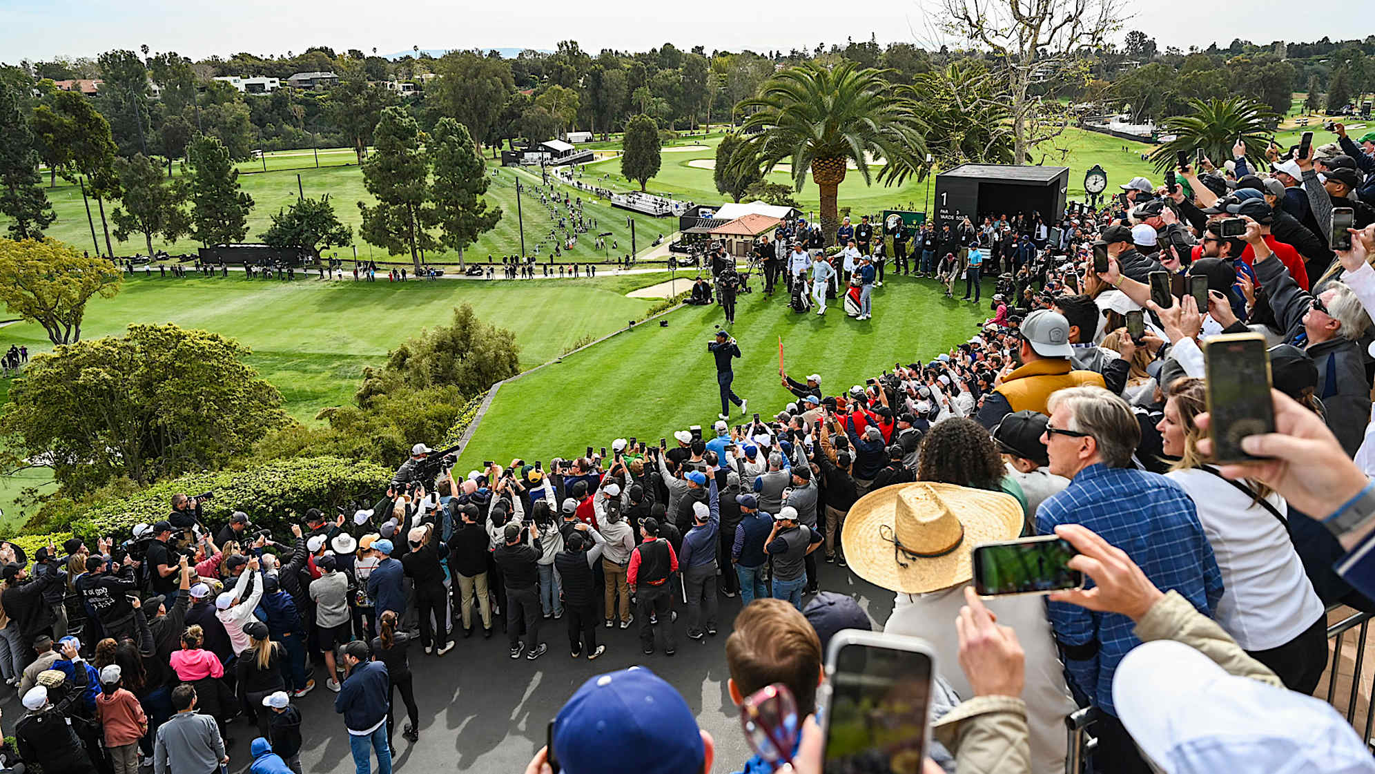 PACIFIC PALISADES, CA - FEBRUARY 16:  Fans record with their mobile phones and watch as Tiger Woods plays his shot from the first tee during the first round of the Genesis Invitational at Riviera Country Club on February 16, 2023 in Pacific Palisades, California. (Photo by Keyur Khamar/PGA TOUR via Getty Images)