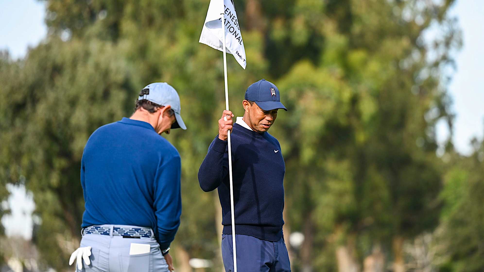 PACIFIC PALISADES, CA - FEBRUARY 16:  Tiger Woods smiles as he pulls the pinflag for Rory McIlroy of Northern Ireland on the 12th hole green during the first round of the Genesis Invitational at Riviera Country Club on February 16, 2023 in Pacific Palisades, California. (Photo by Keyur Khamar/PGA TOUR via Getty Images)
