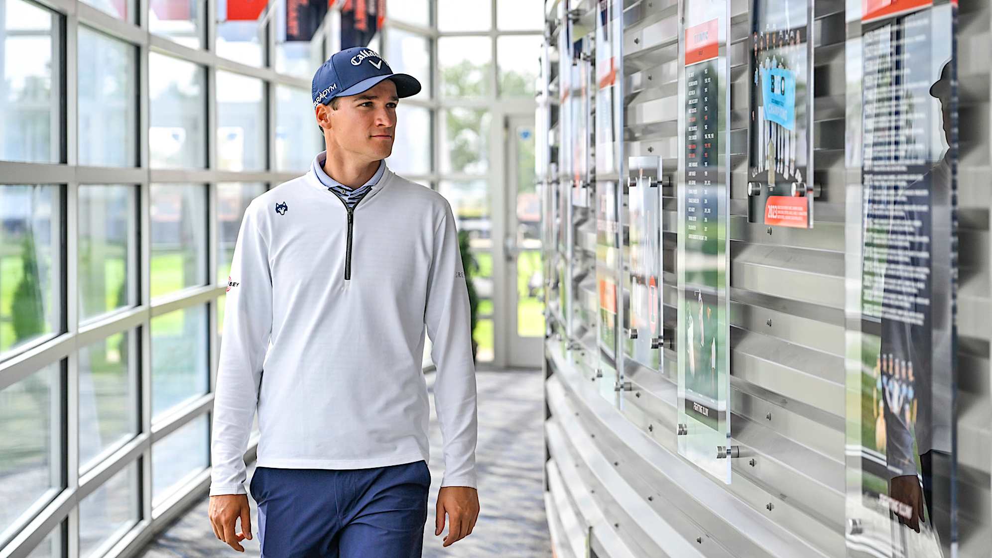 CHAMPAIGN, ILLINOIS - SEPTEMBER 28:  Adrien Dumont de Chassart walks past awards on display in the Demirjian Golf Practice Facility at the University of Illinois on September 28, 2023 in Champaign, Illinois. (Photo by Ben Jared/PGA TOUR)
