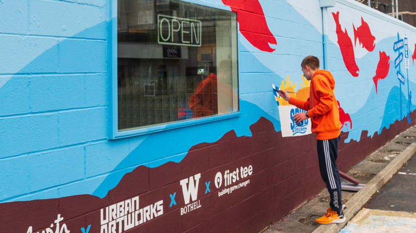 Austin Picinich paints the Save Our Salmon” (SOS) Mural along Juanita Creek , Seattle. (Courtesy Austin Picinich)