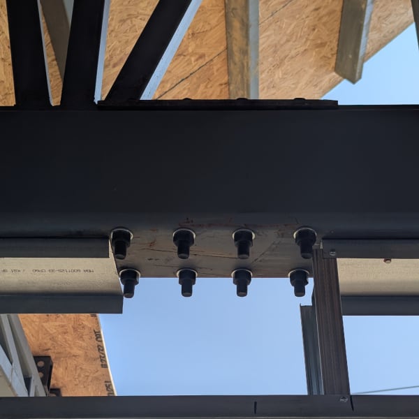 Bolted red-iron structural steel connection at the truss line