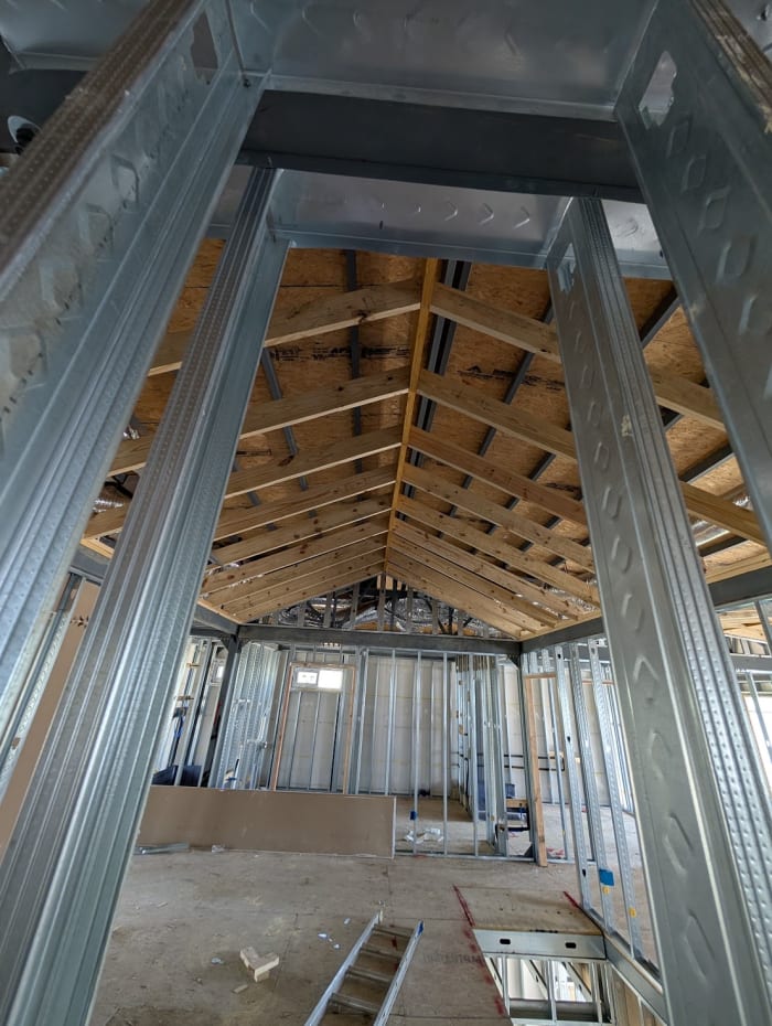 Eye-level view up through steel structural columns to the roof truss skeleton during construction of a My Castle Homes build