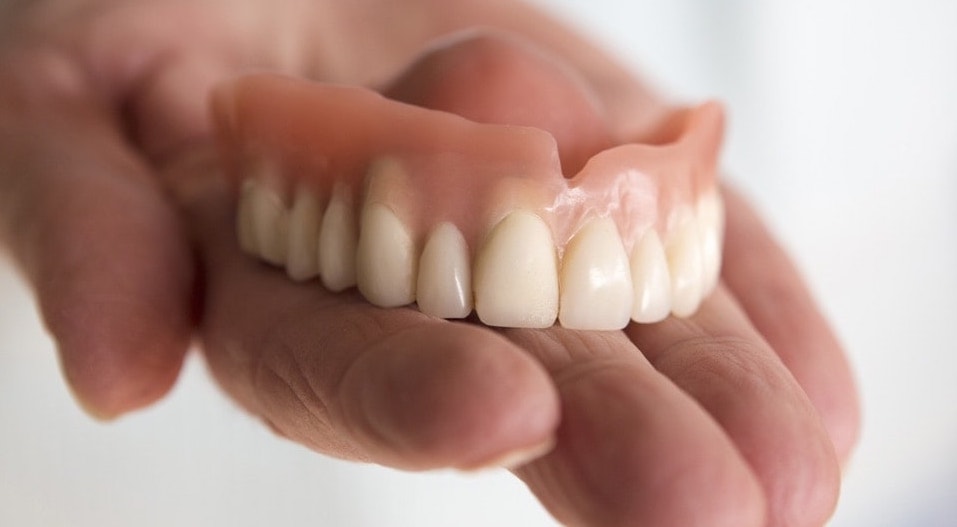 A denture on the palm of a hand