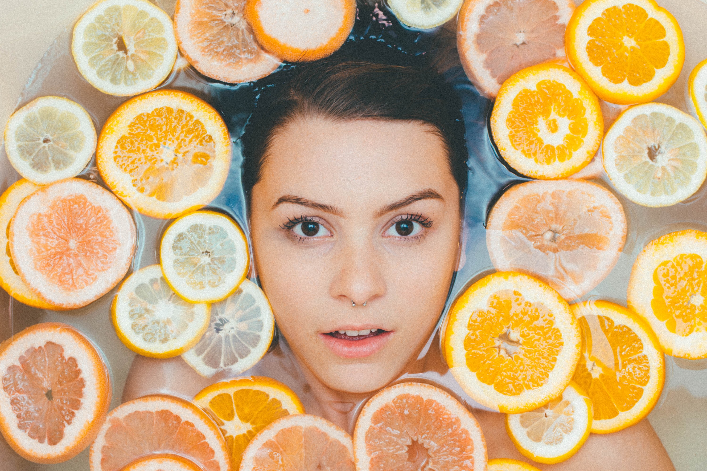 Face surrounded by fruits. Photo by Noah Buscher on Unsplash.