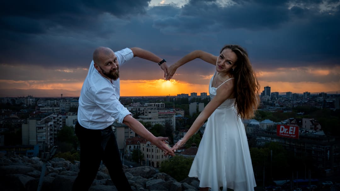 Man and woman making a heart with their hands at sunset