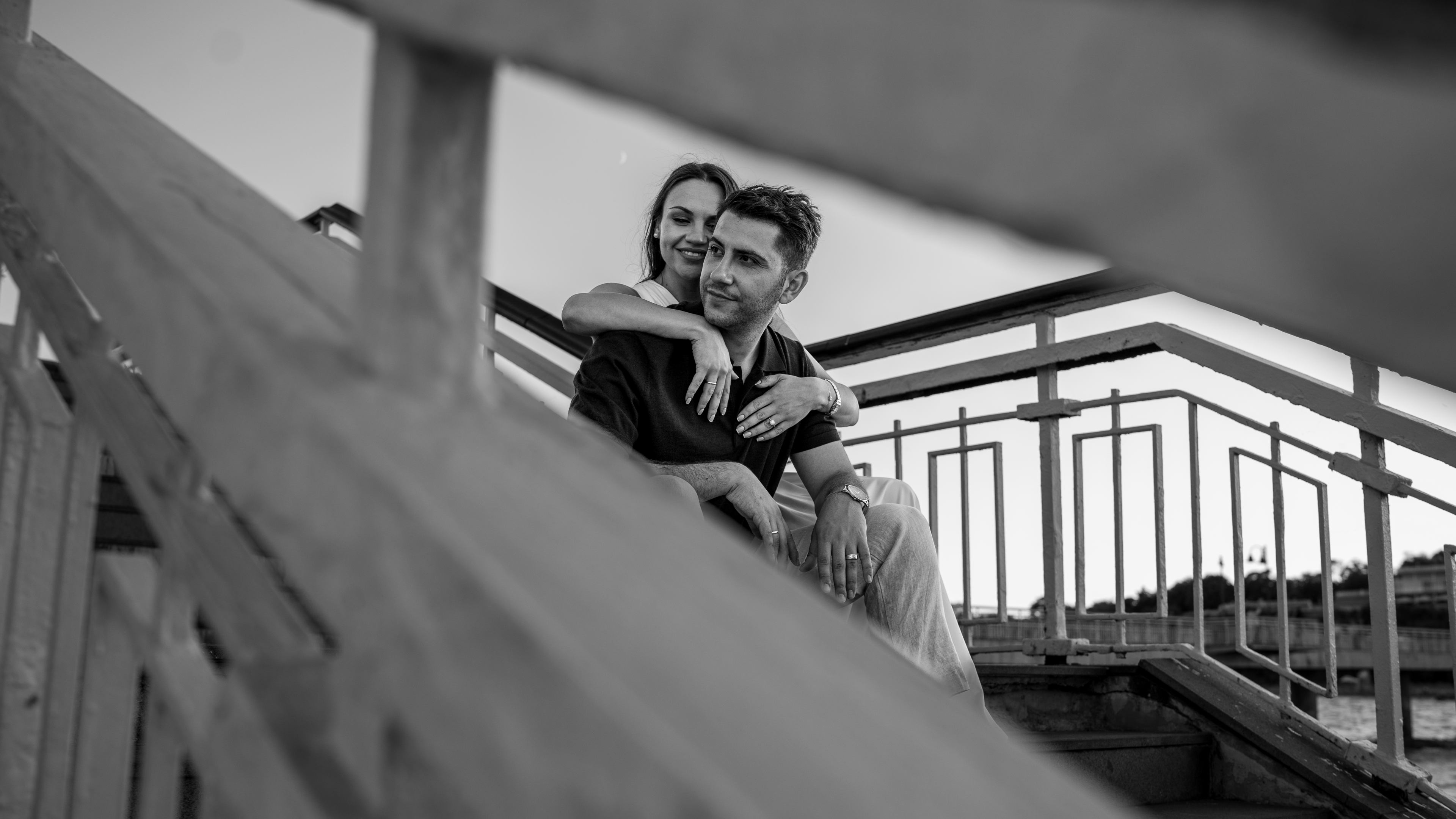 A young couple embracing on the pier steps.