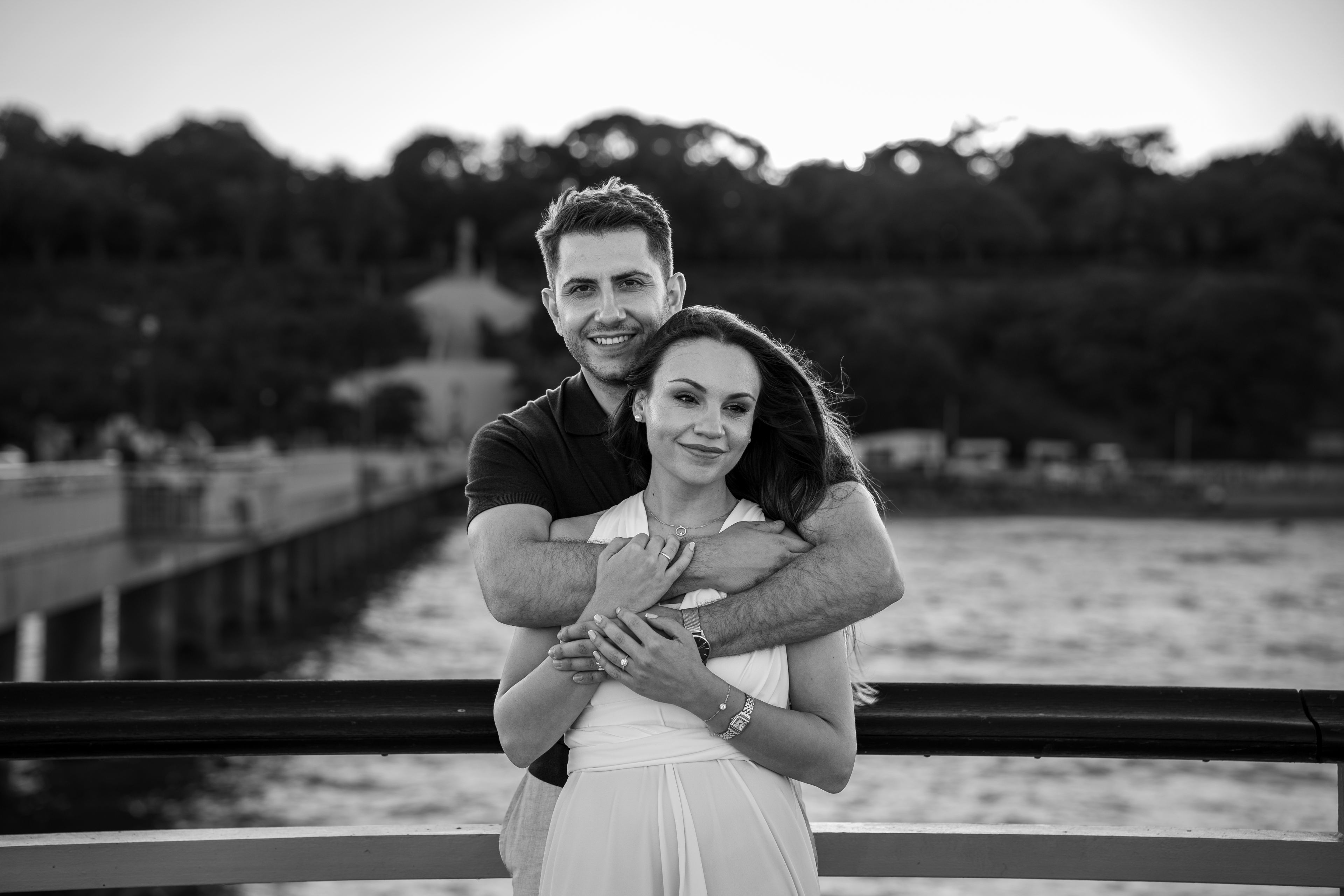 A young couple embracing on the seaside pier and gazing dreamily.