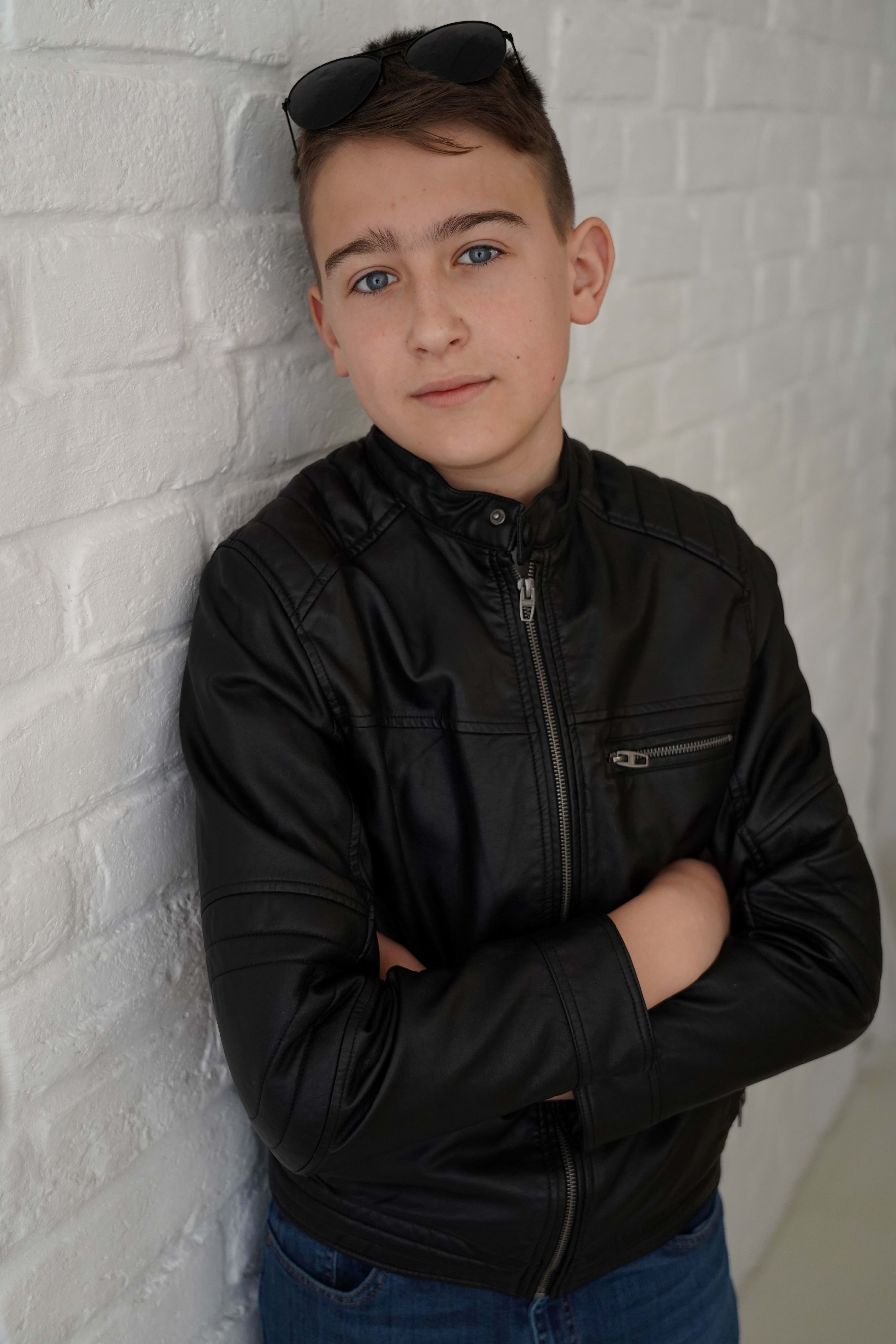 Boy in leather jacket by white wall