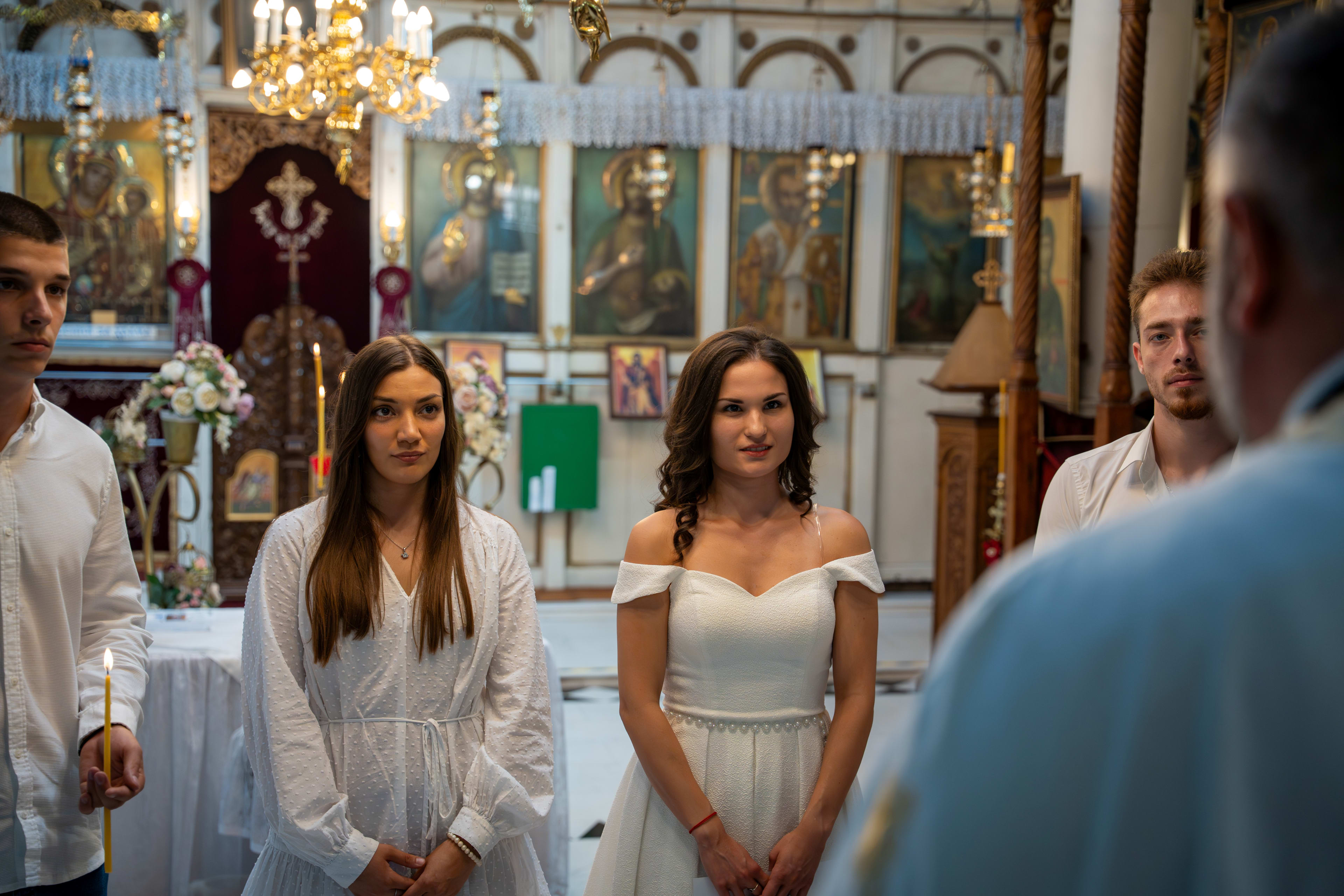 Jente som blir døpt i en kirke, sammen med sine gjester og venner. Alle er kledd i hvitt. En prest står foran dem.