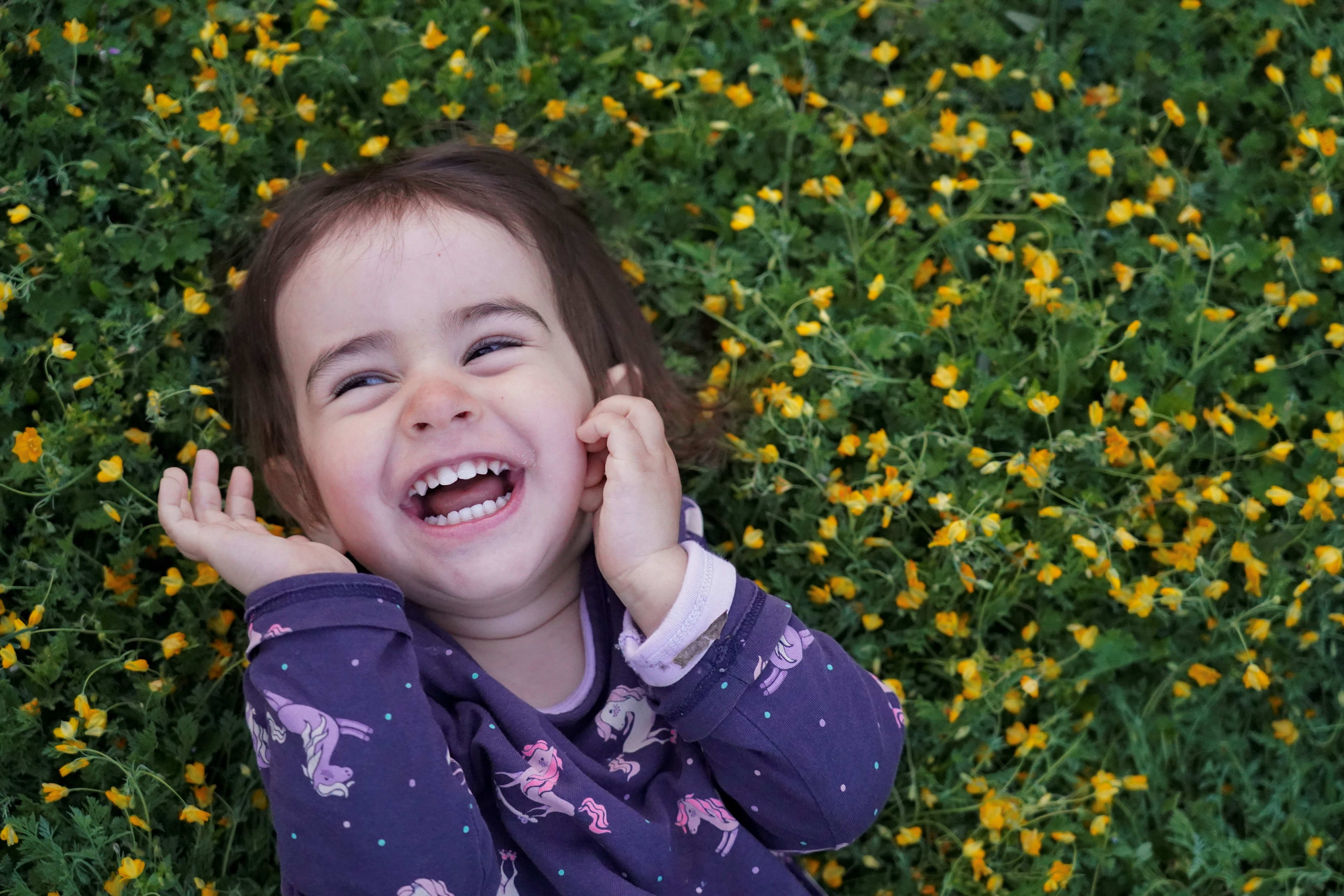 Child laughing among yellow flowers