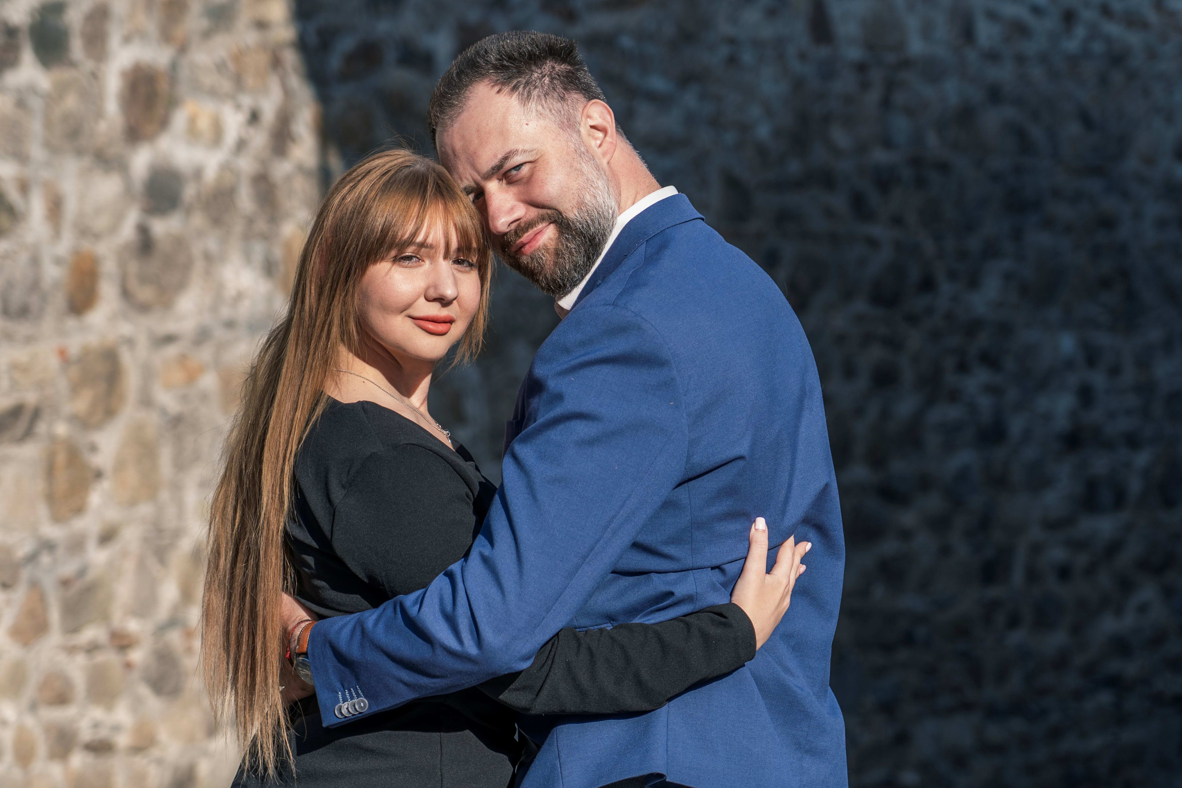 Couple hugging by a stone wall