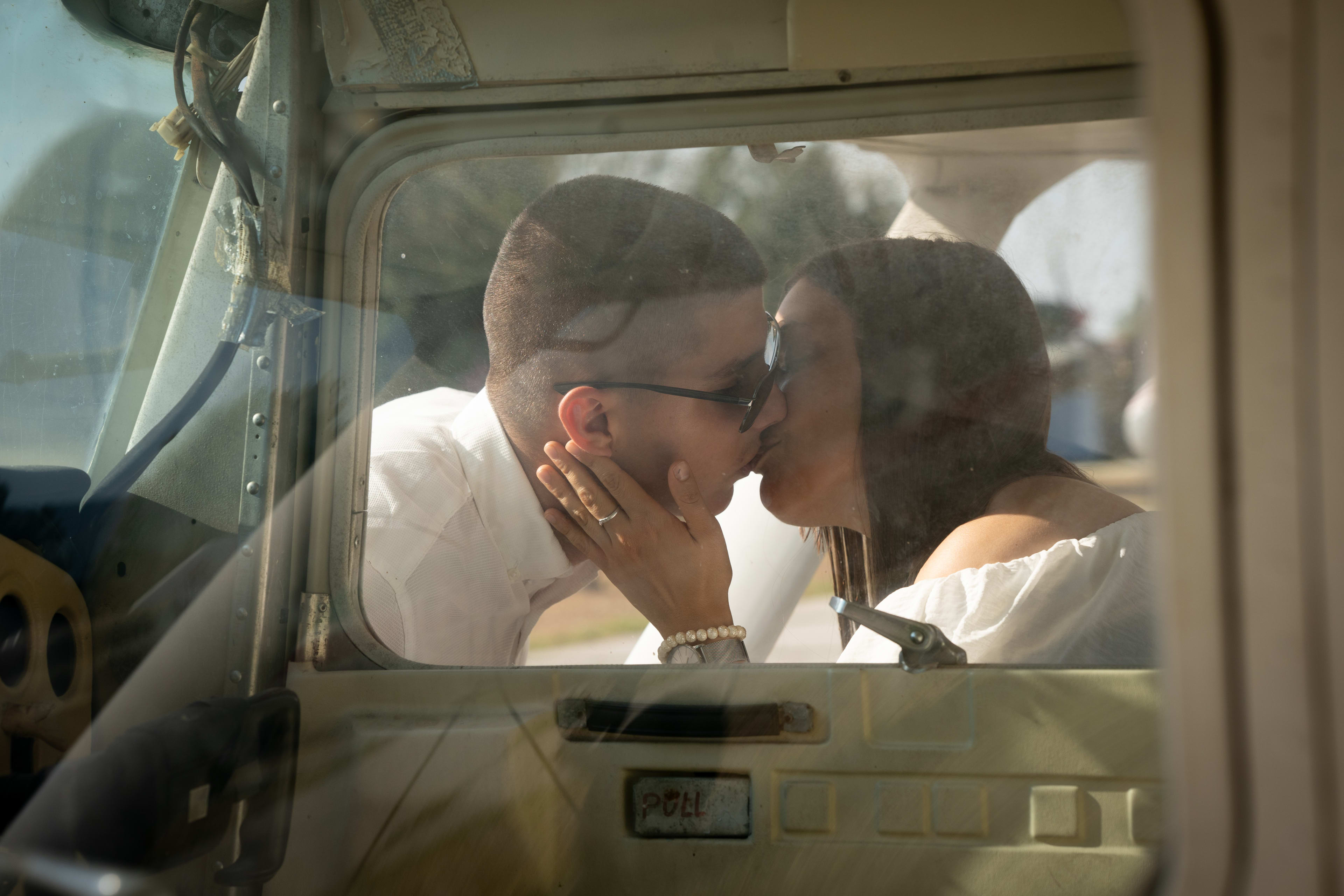 Boy and girl kissing behind the cockpit of an old airplane. The photo is taken through the foggy glass of the plane.