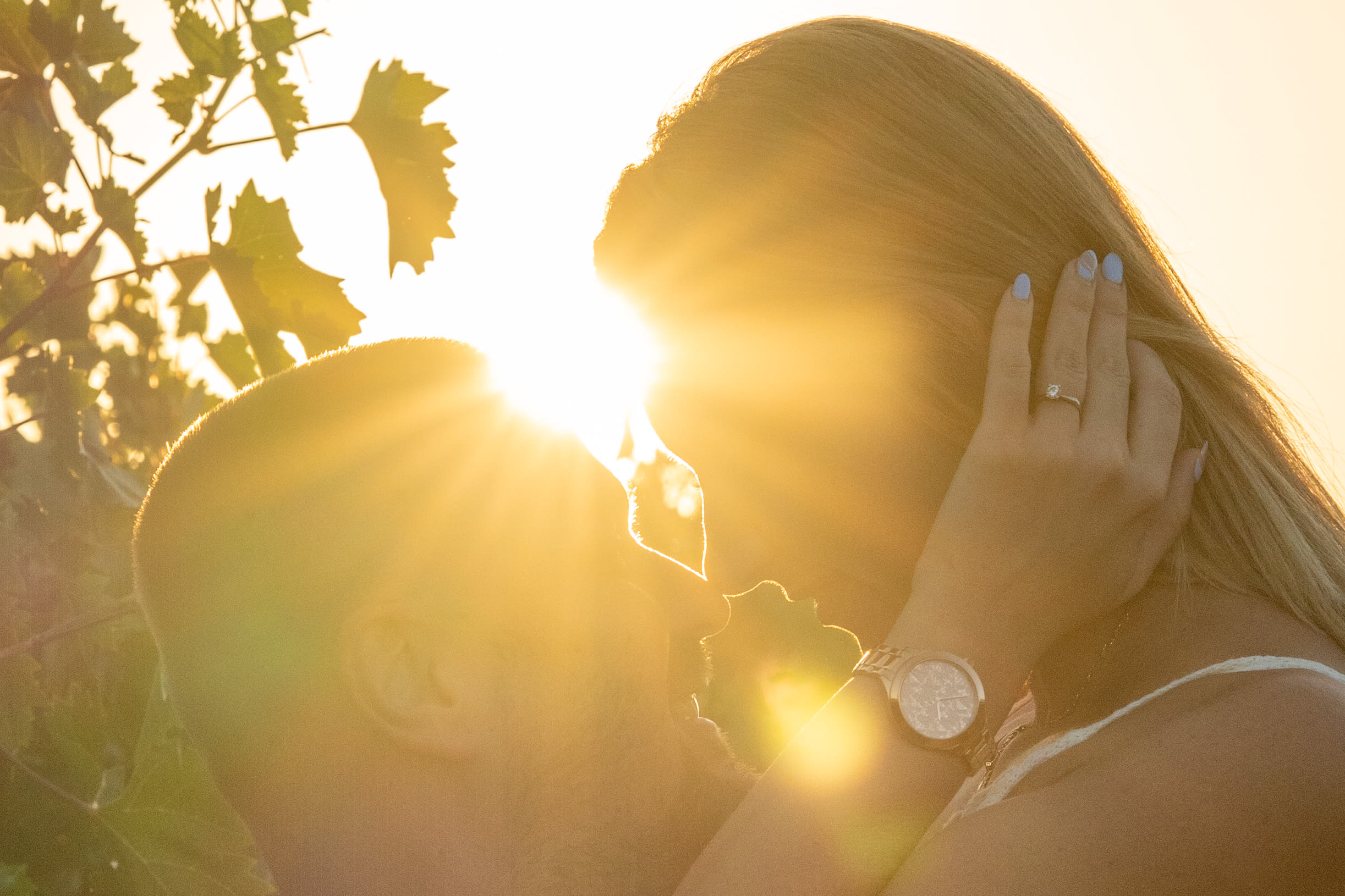 Man and woman looking lovingly at each other, touching foreheads. Sunlight passes right between them. The woman is in a white dress, the man is in a white shirt, and they are holding hands.