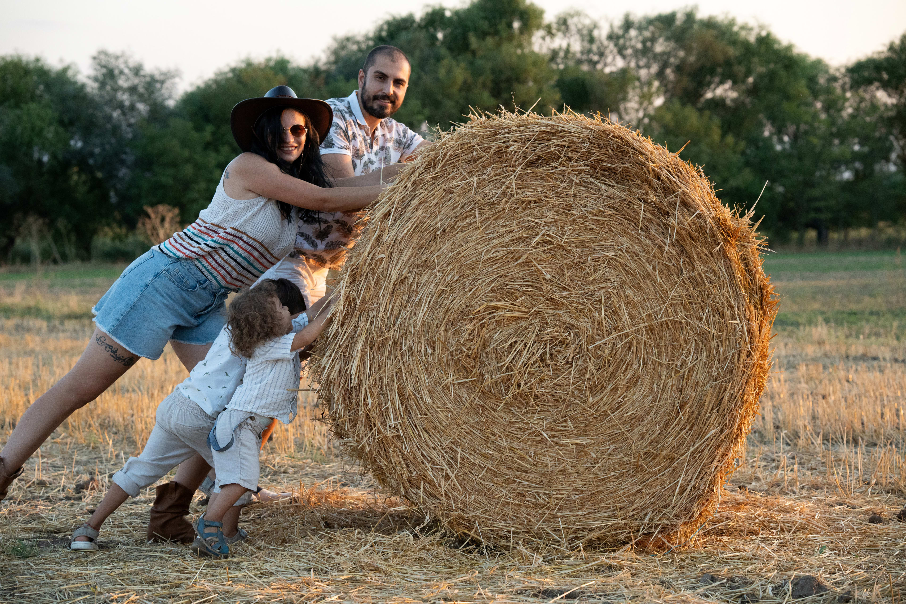 Family pushes a straw bale while laughing and having fun