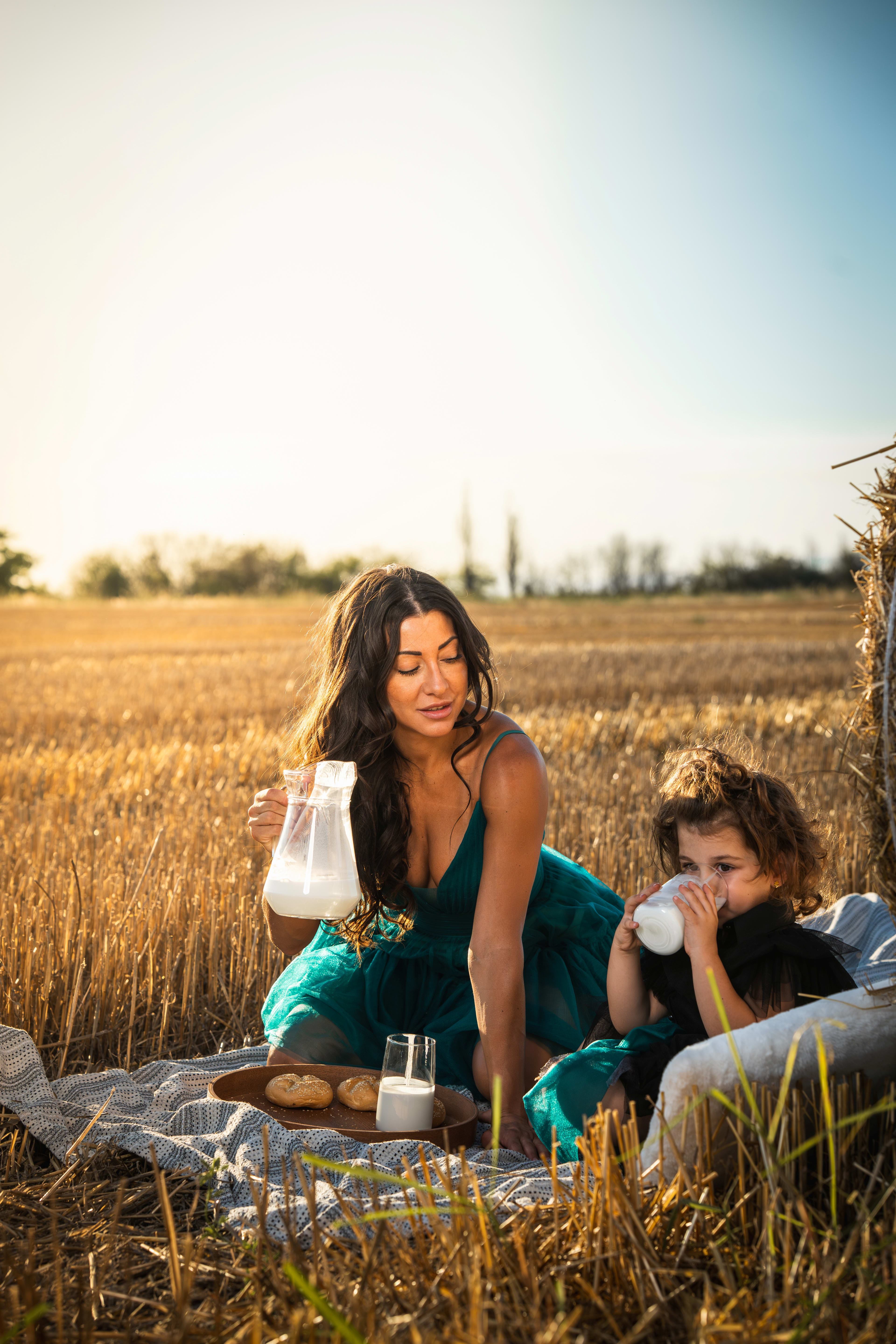 Mother and daughter drinking milk on straw bales.