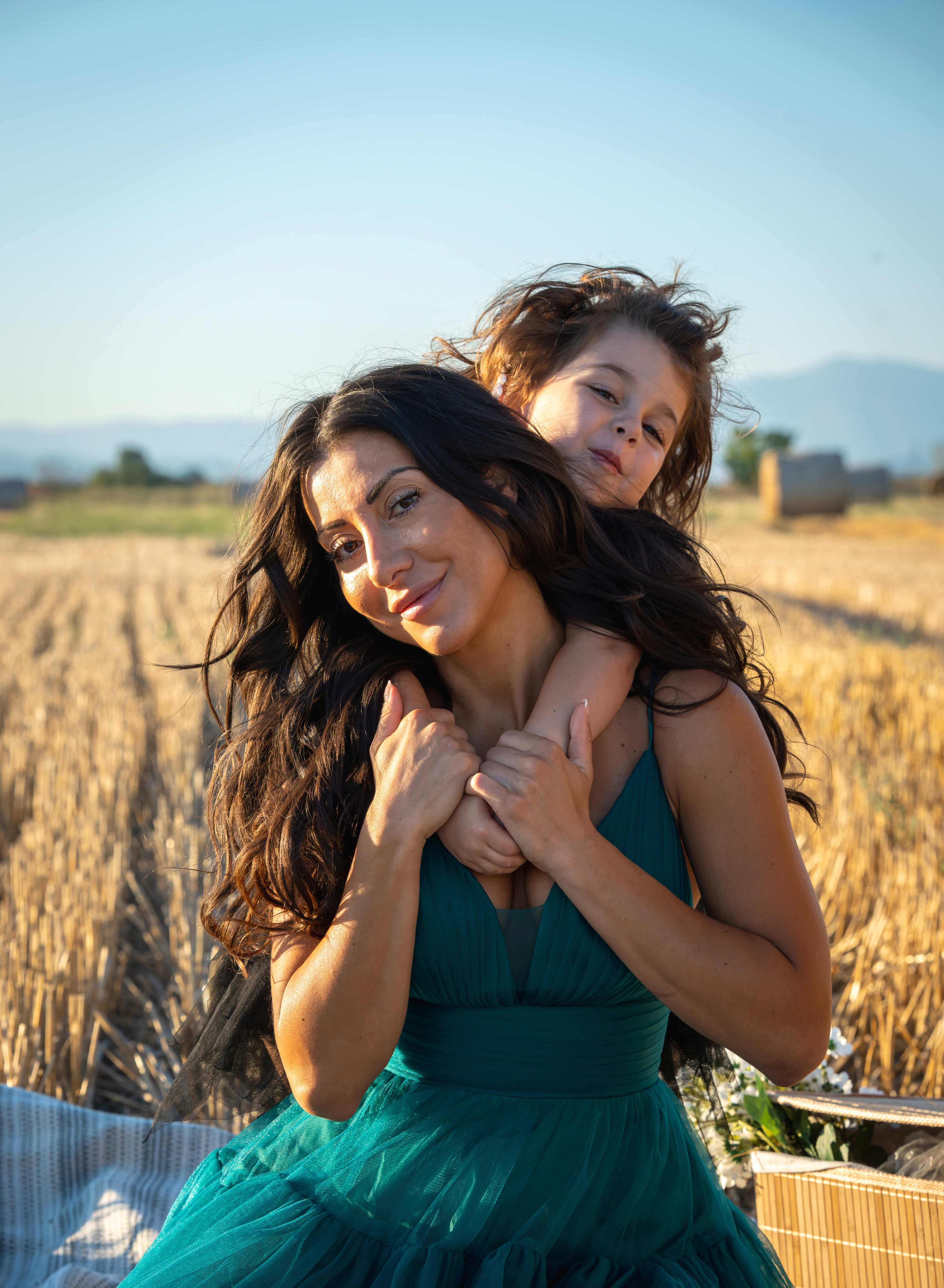 Mother and daughter hug in a field of straw and straw bales