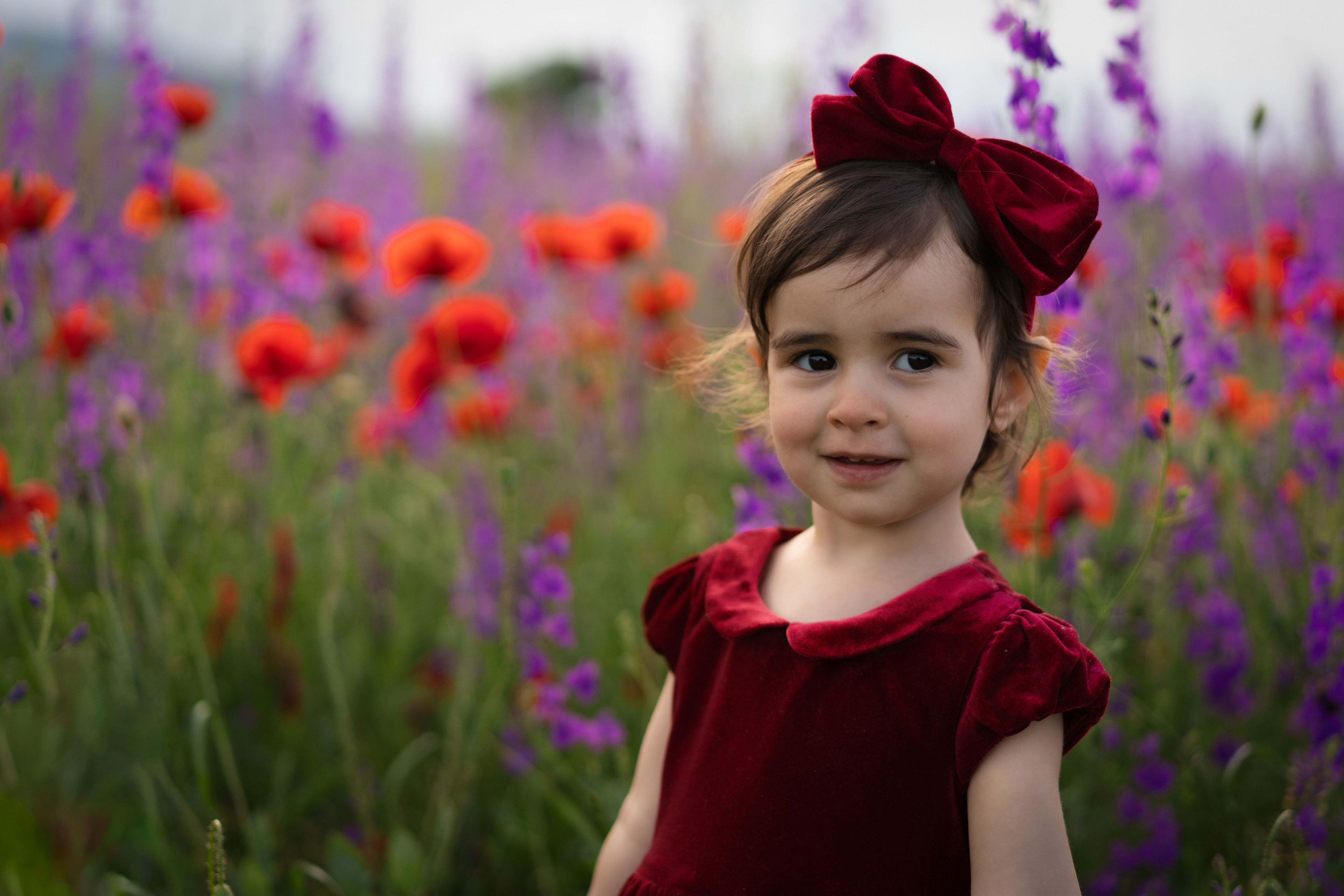Small child with red bow in colorful field