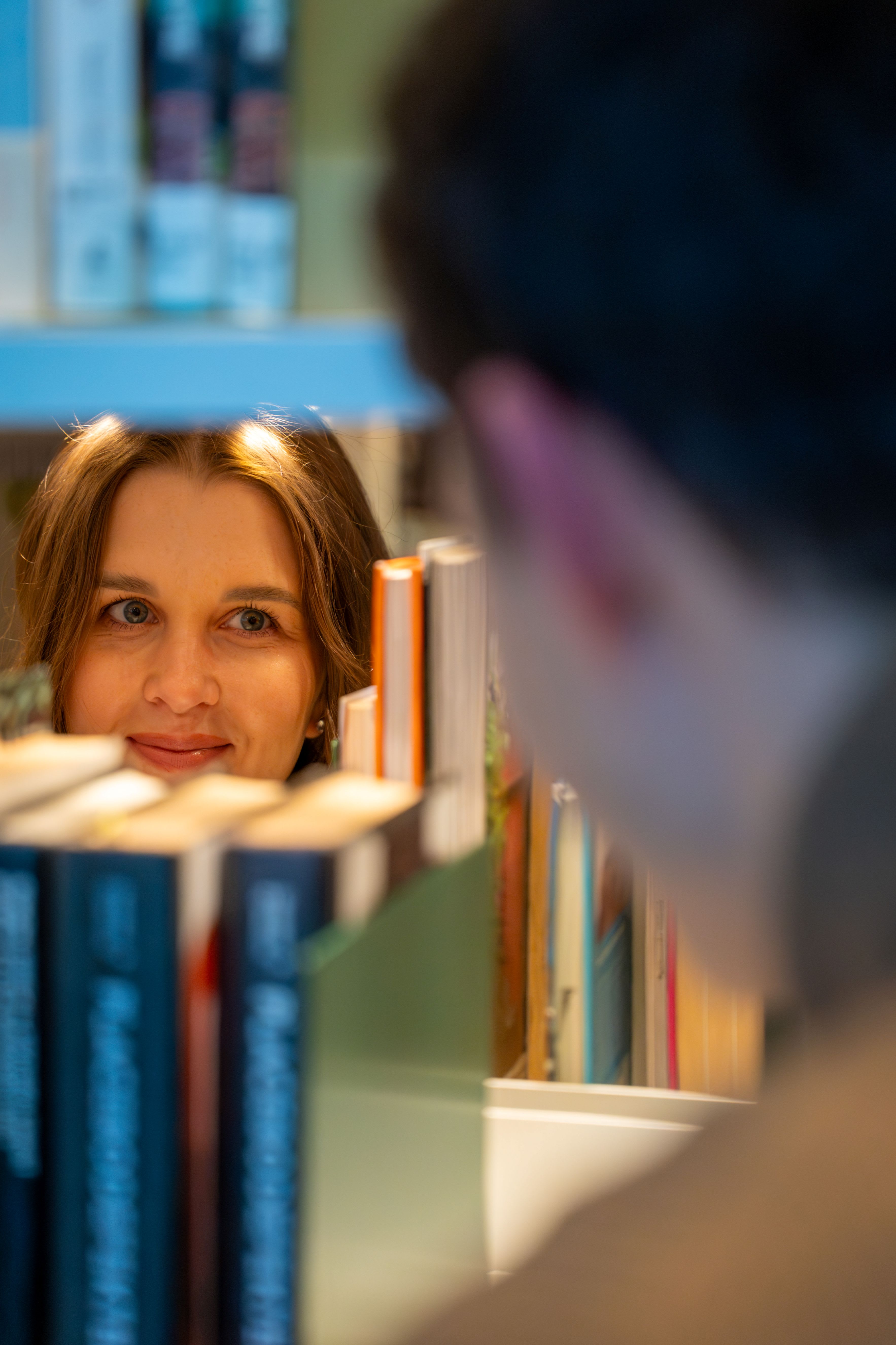 Woman peeking behind a bookshelf
