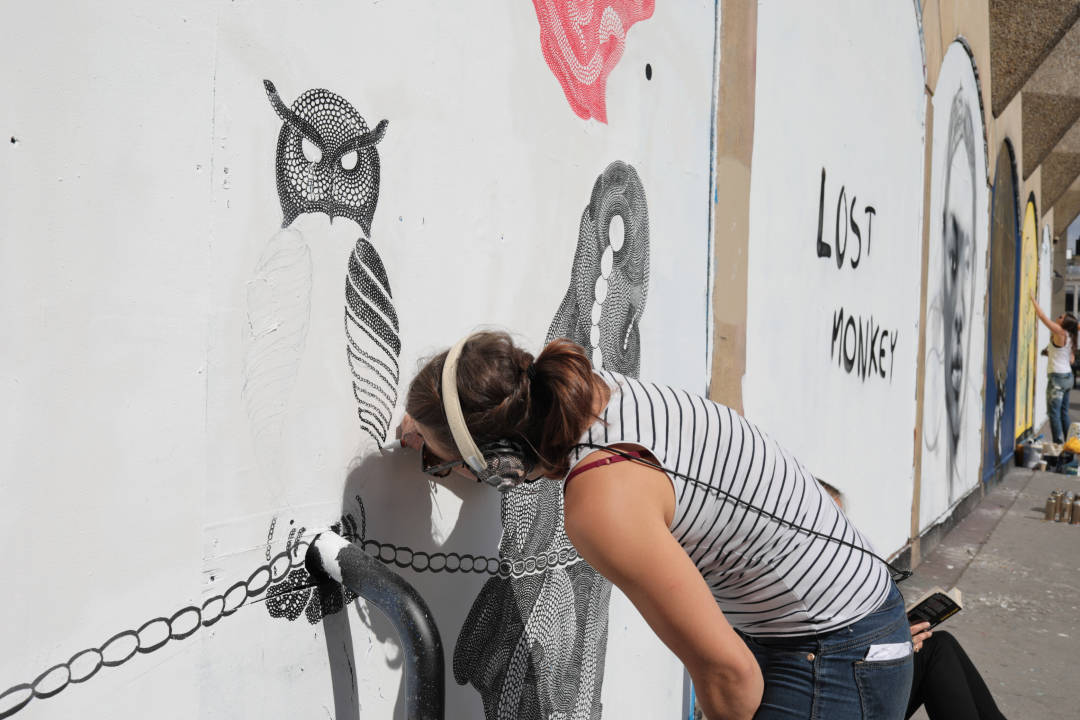 Photo of an artist carefully drawing on a wall