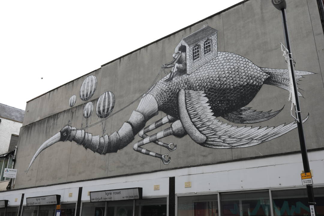 Photo of a giant painting on a building of a man in a shed riding a giant bird