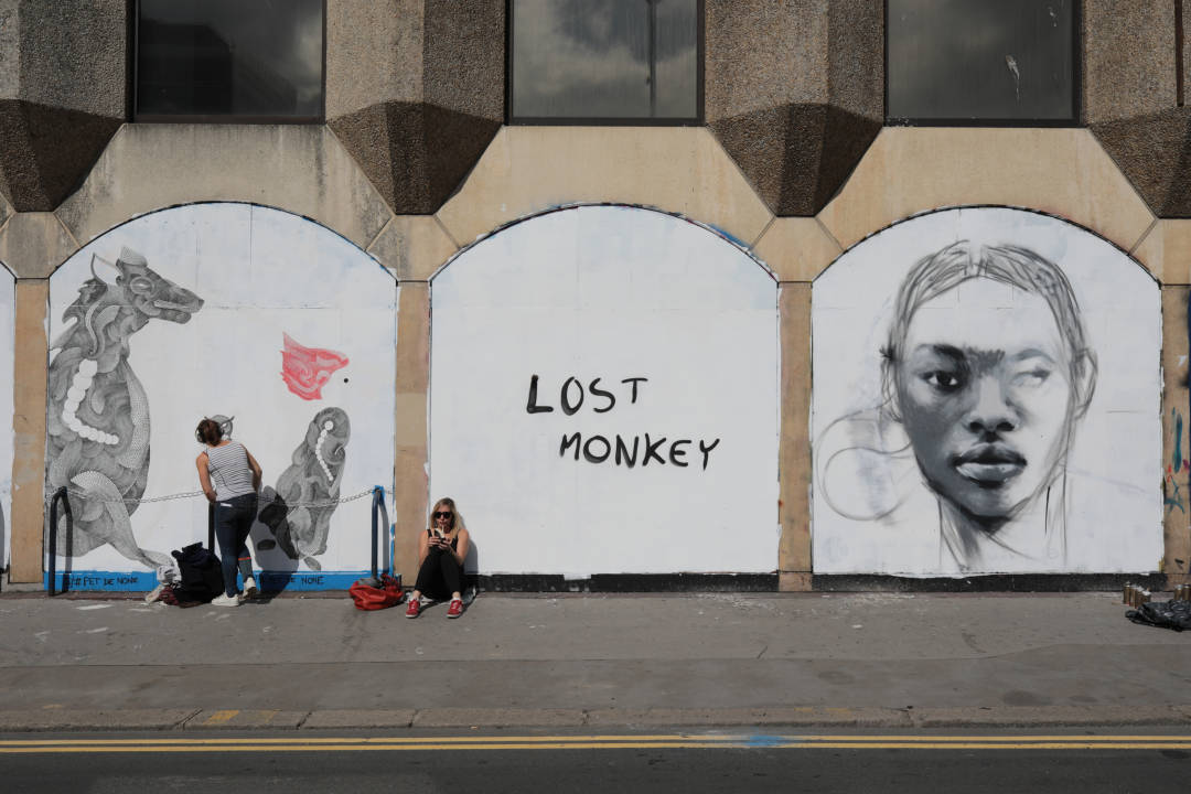 Photo of an artist starting to paint on a white hoarding