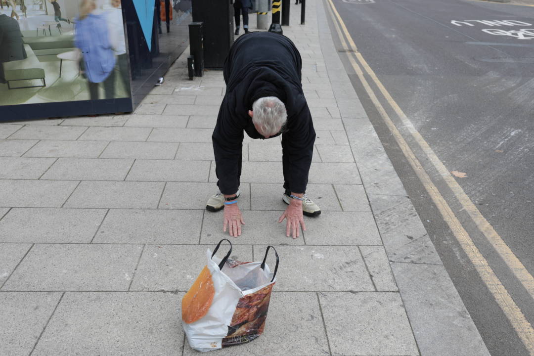 Photo of a man touching the floor on a street