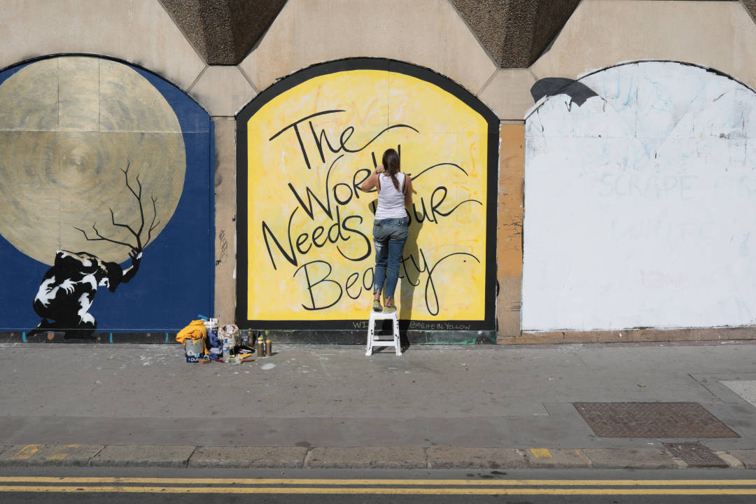 Photo of an artist writing a mural