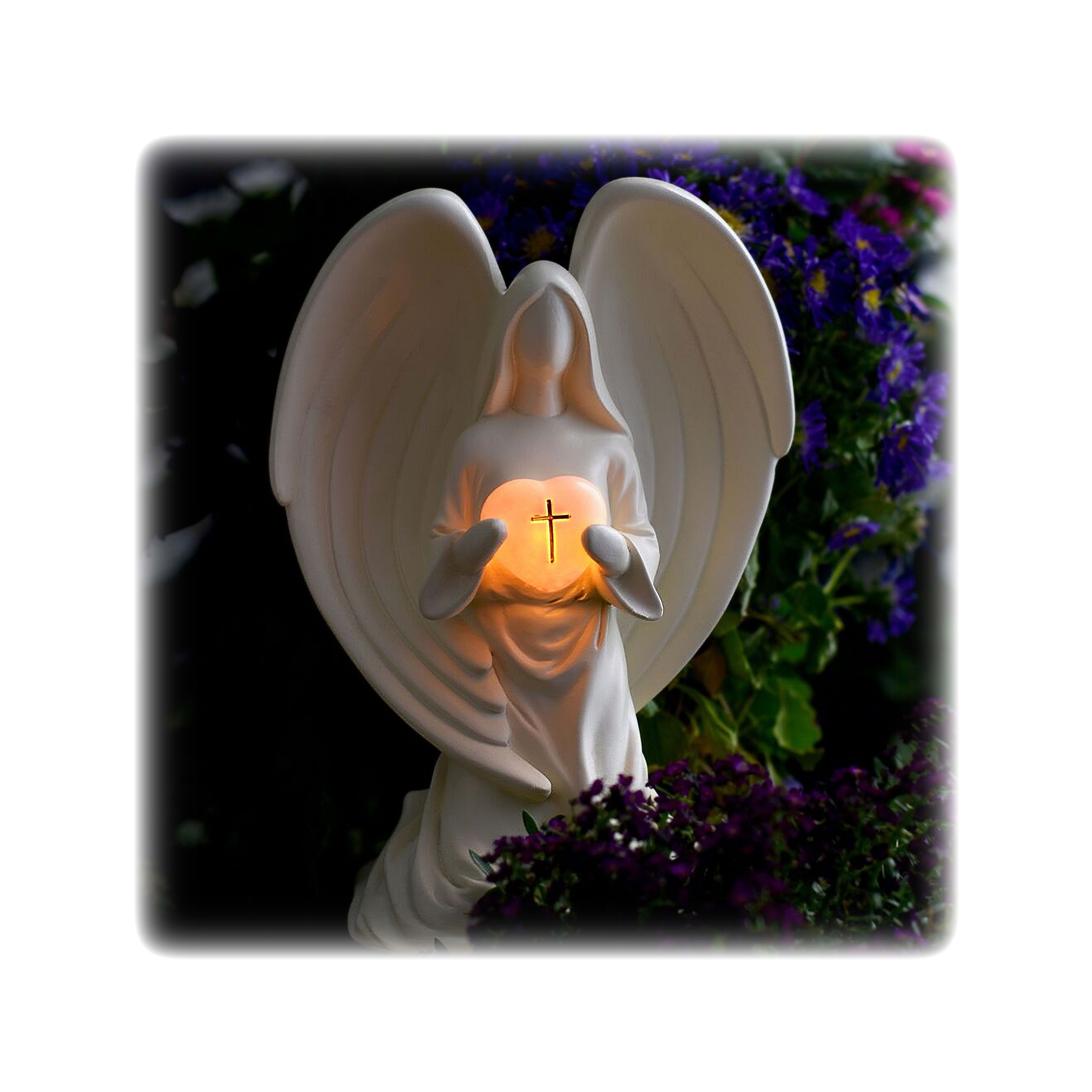 An elegant angel statue cradles a warm light, immersed in colorful floral surroundings at dusk.