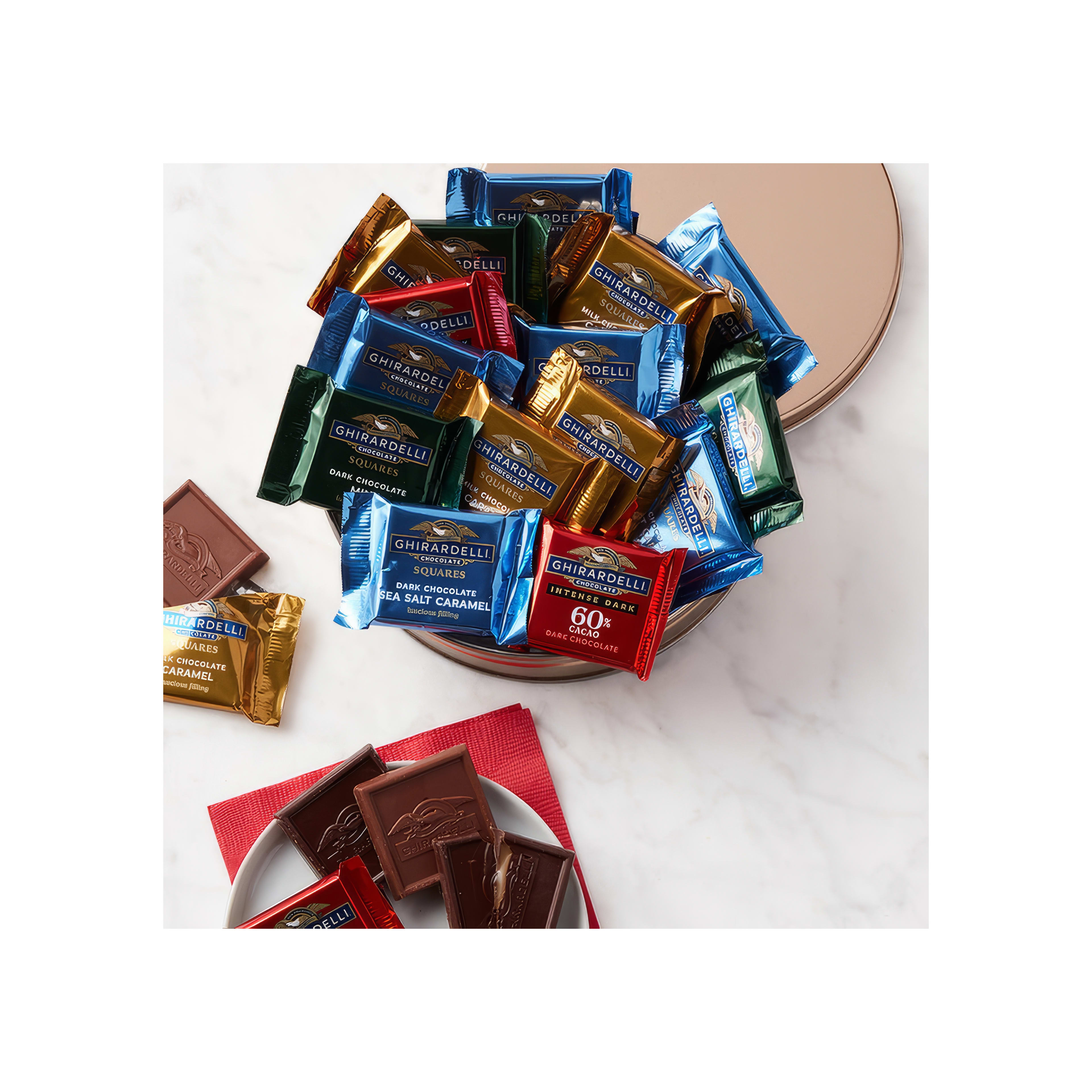 Delicious chocolate squares in various flavors placed in a decorative tin on a white surface.