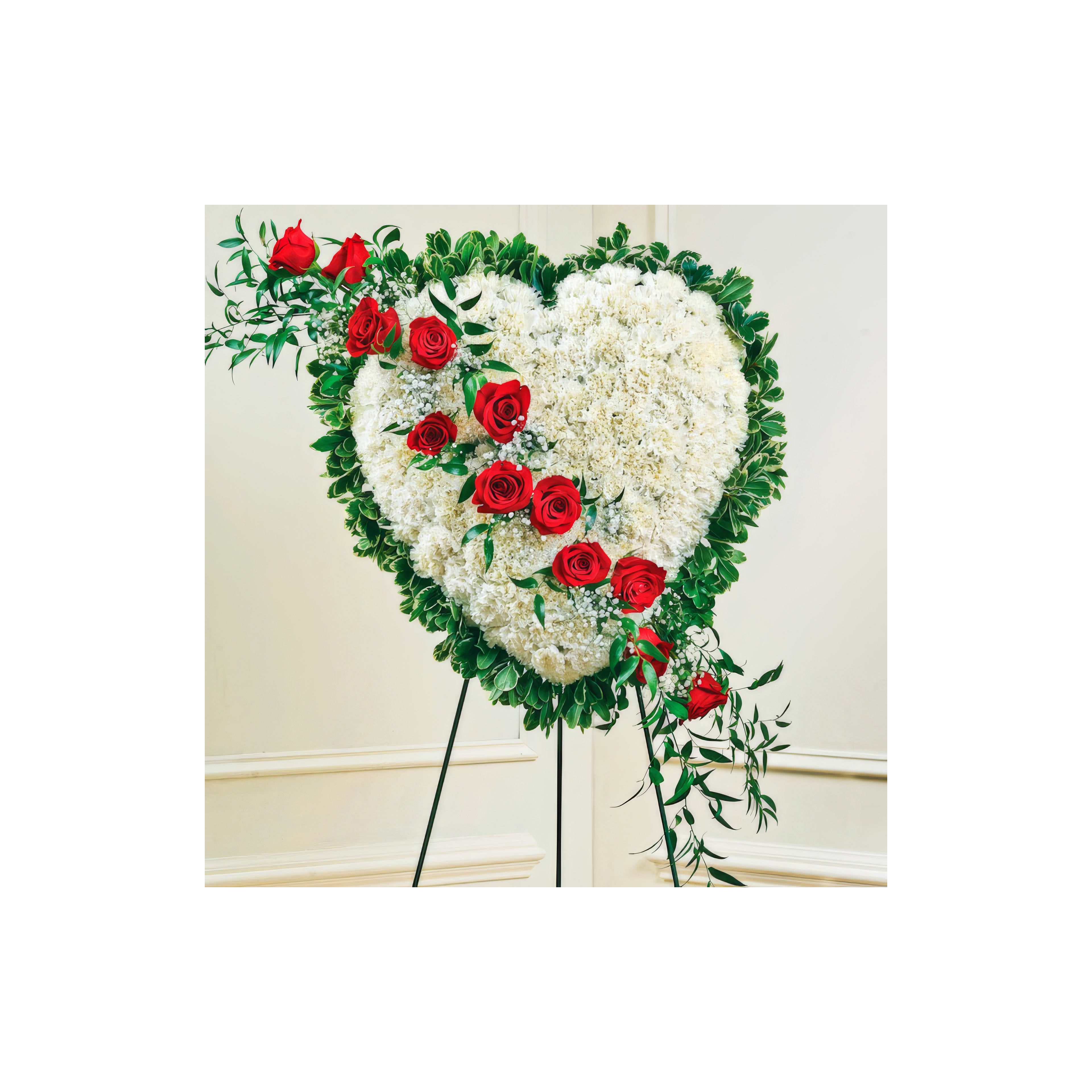 A heart-shaped floral arrangement of red roses and white flowers symbolizes love and remembrance.