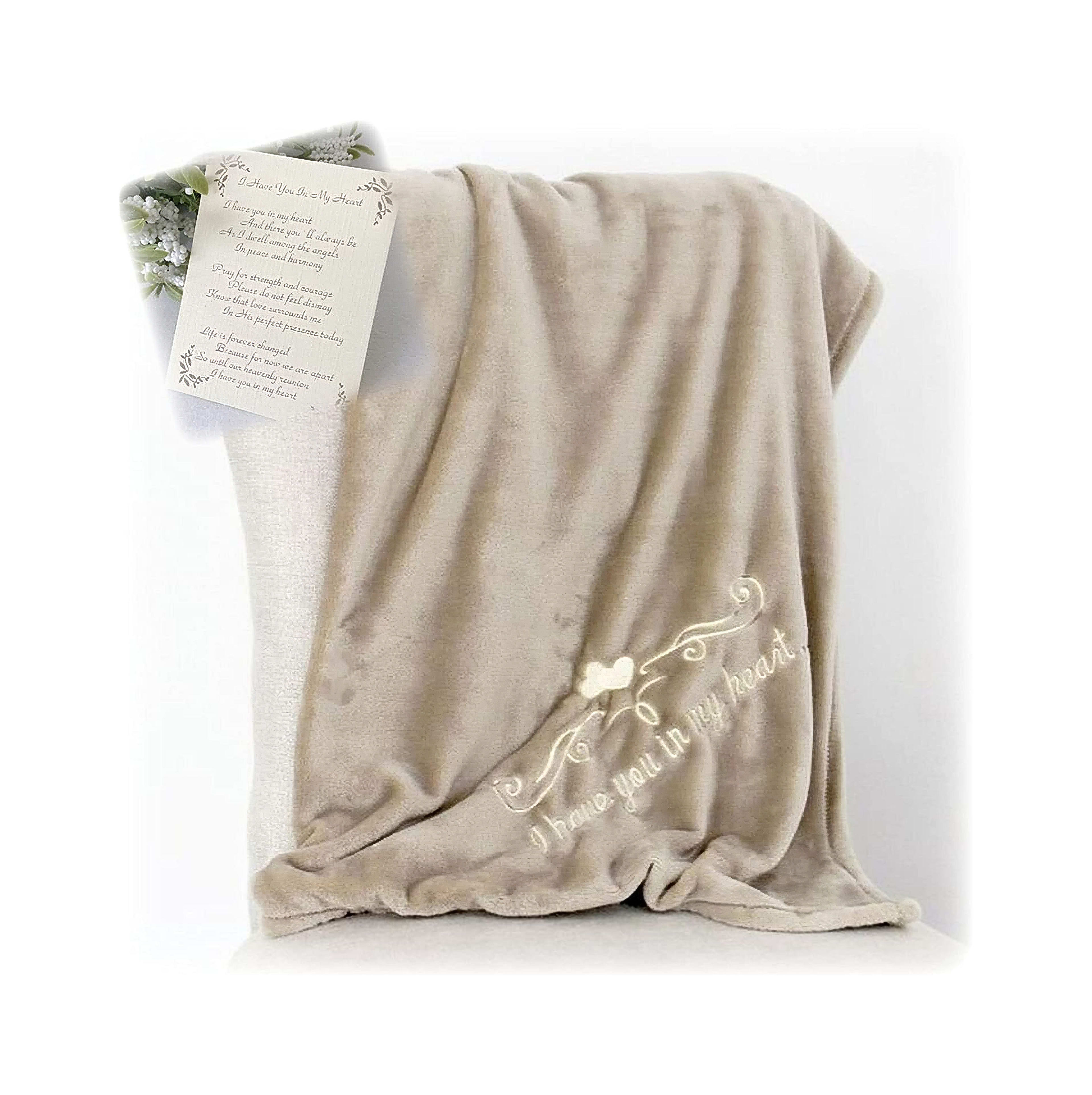A warm beige blanket with delicate embroidery rests on a cushion in a well-lit indoor space.