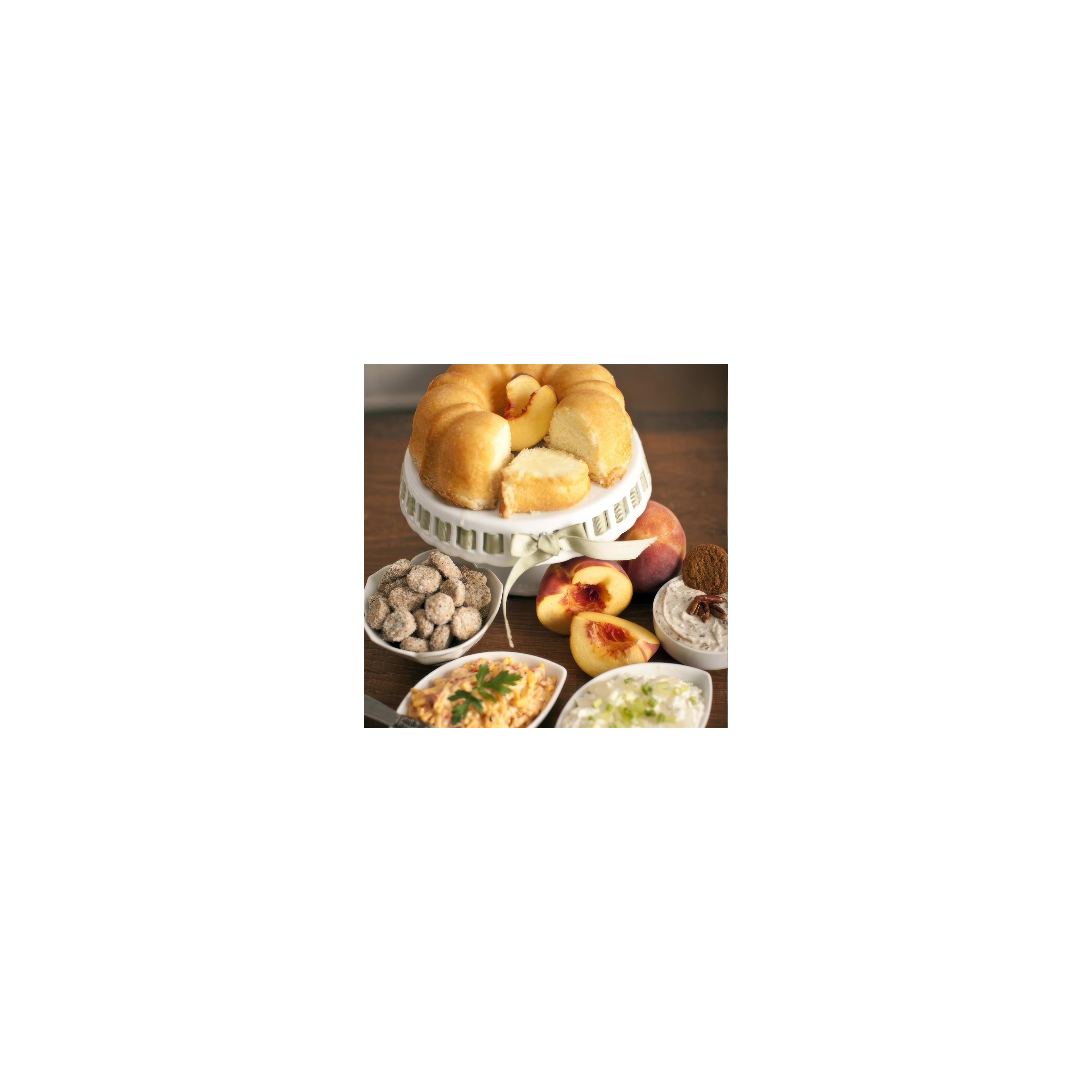 A delicious peach cake is presented with dips and snacks on a wooden table setting.