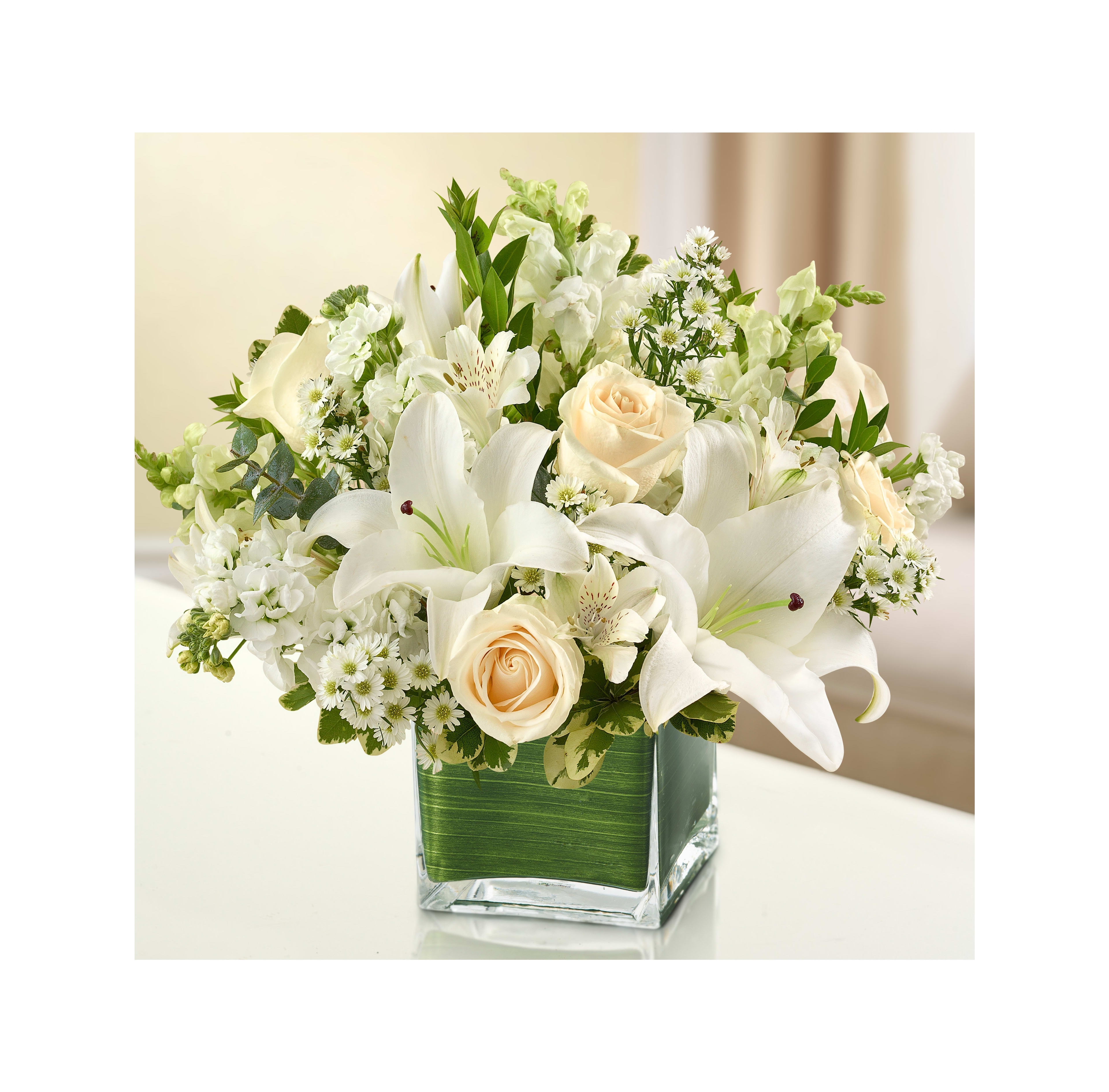 Beautiful white flowers, including lilies and roses, displayed in a glass vase indoors.