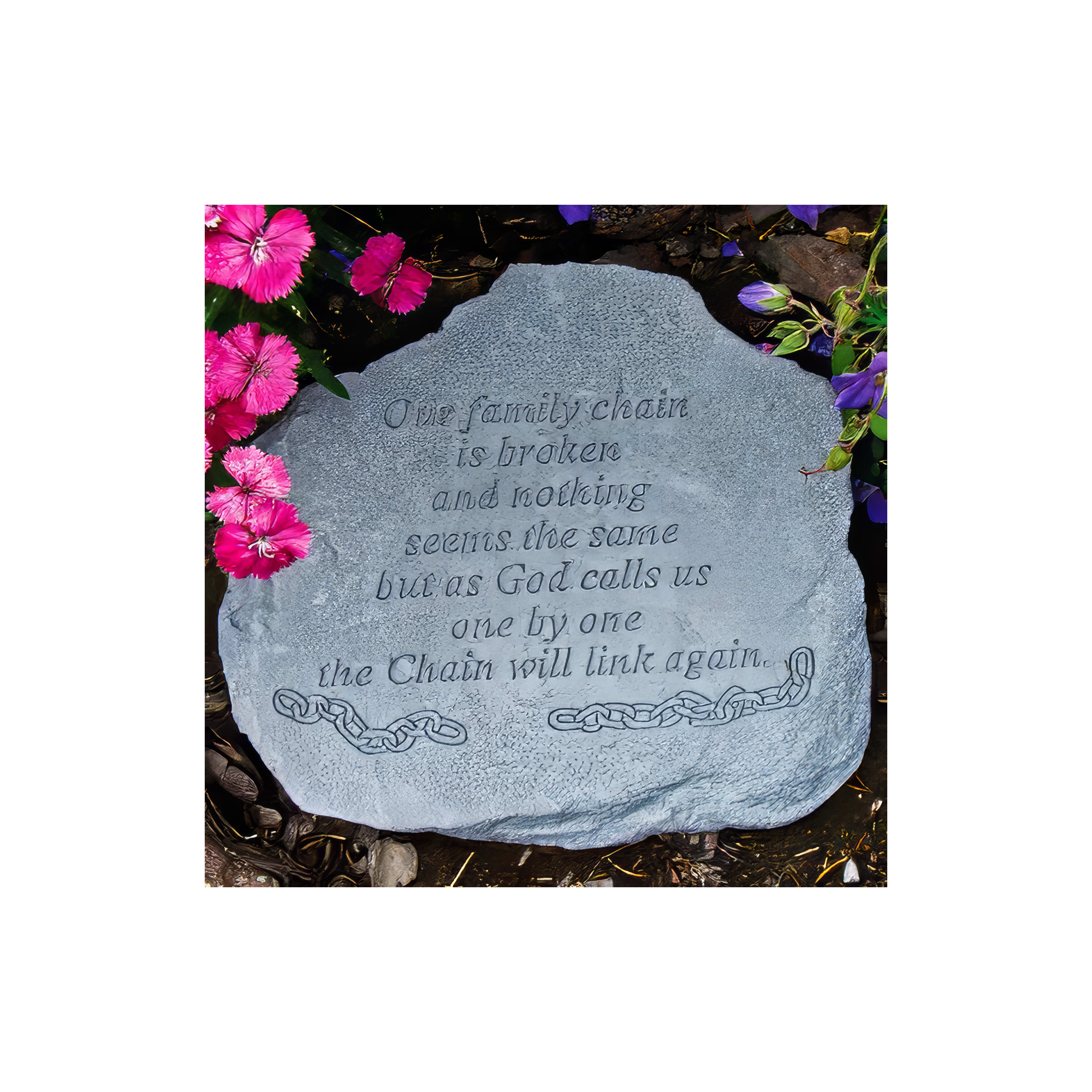 A memorial stone engraved with a touching message rests among colorful flowers in a garden.
