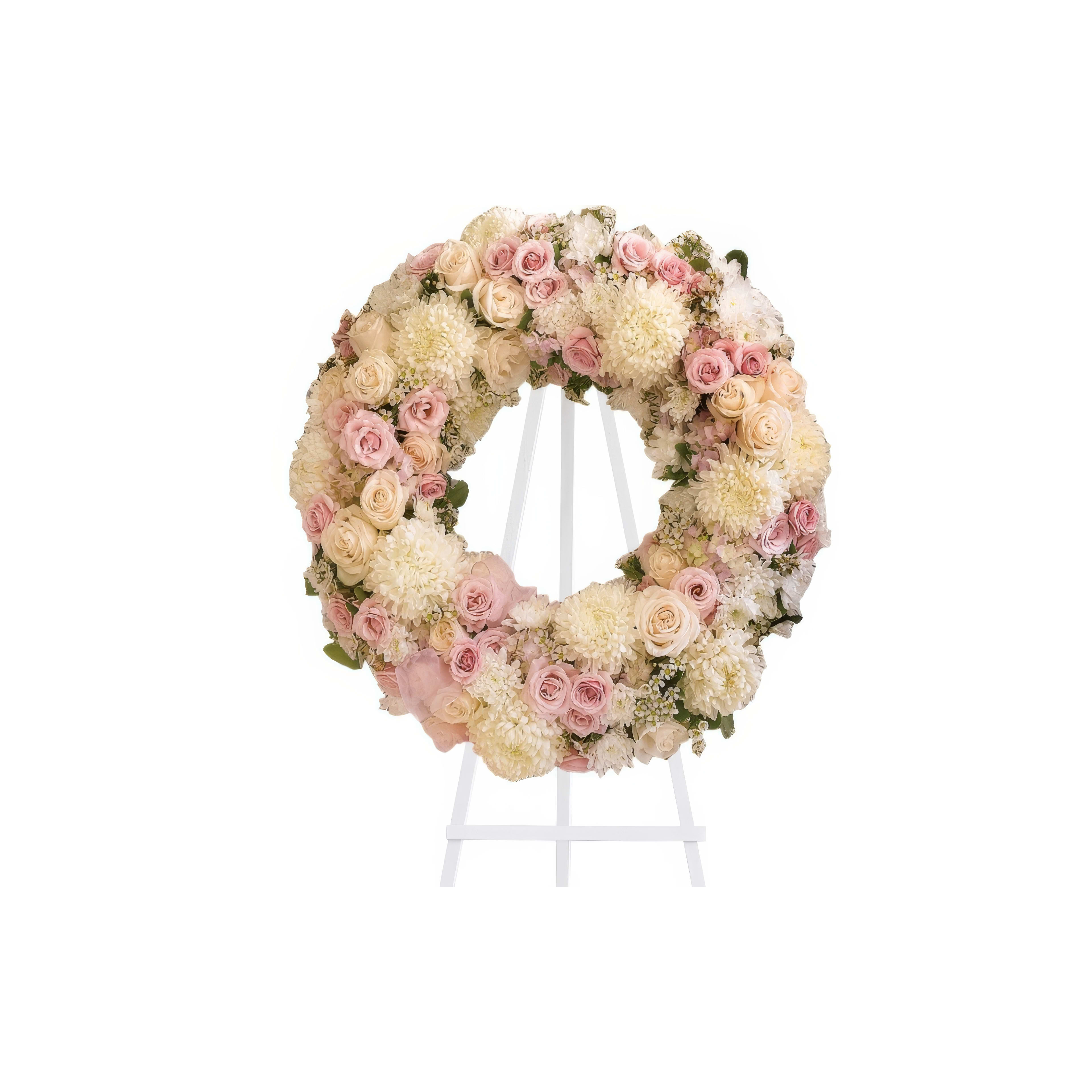 A beautifully arranged wreath of pink and white roses, symbolizing remembrance and love, on a stand.
