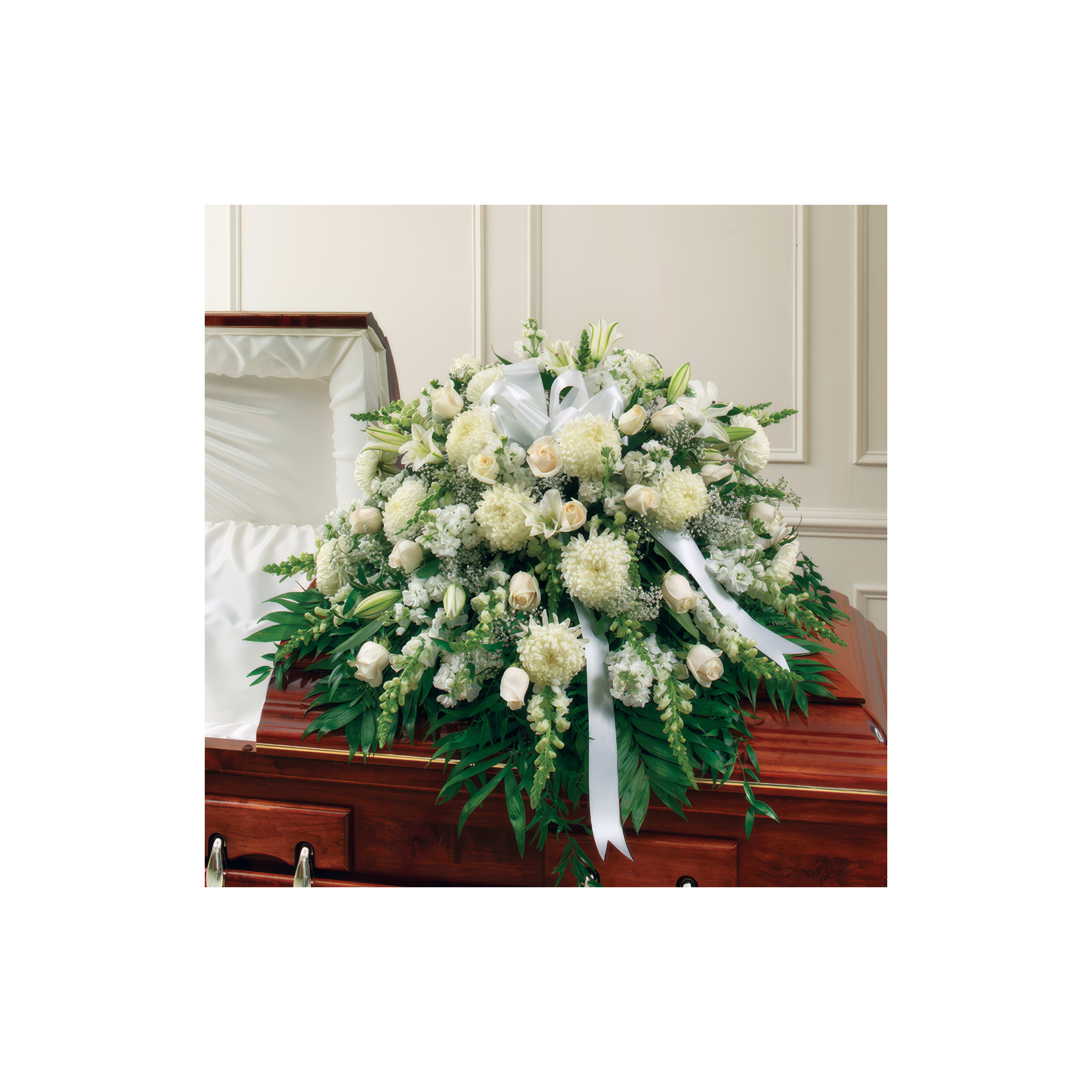 A beautiful arrangement of white flowers decorates a wooden casket during a funeral service.