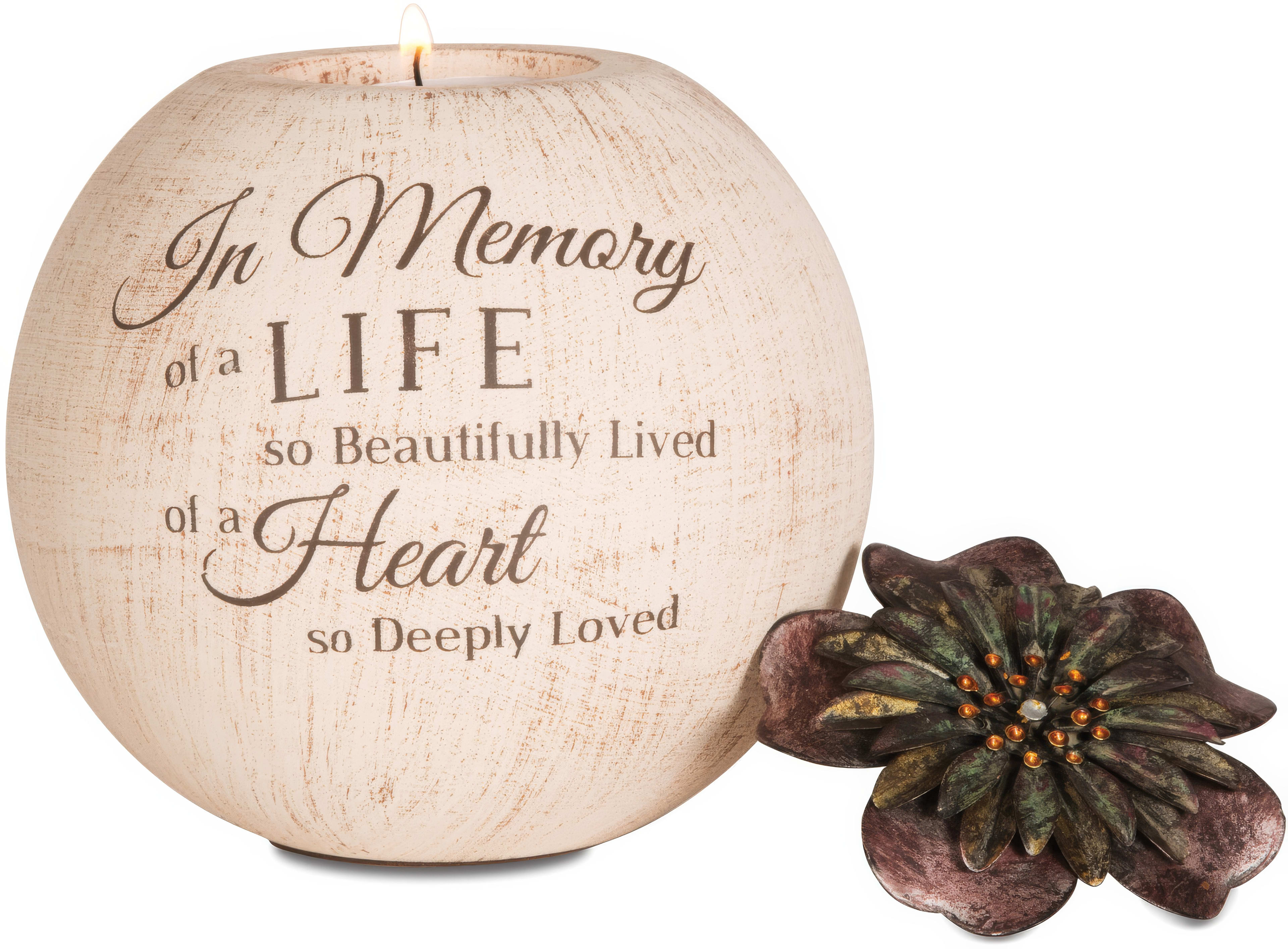 A memorial candle features a touching phrase accompanied by a simple floral decoration.