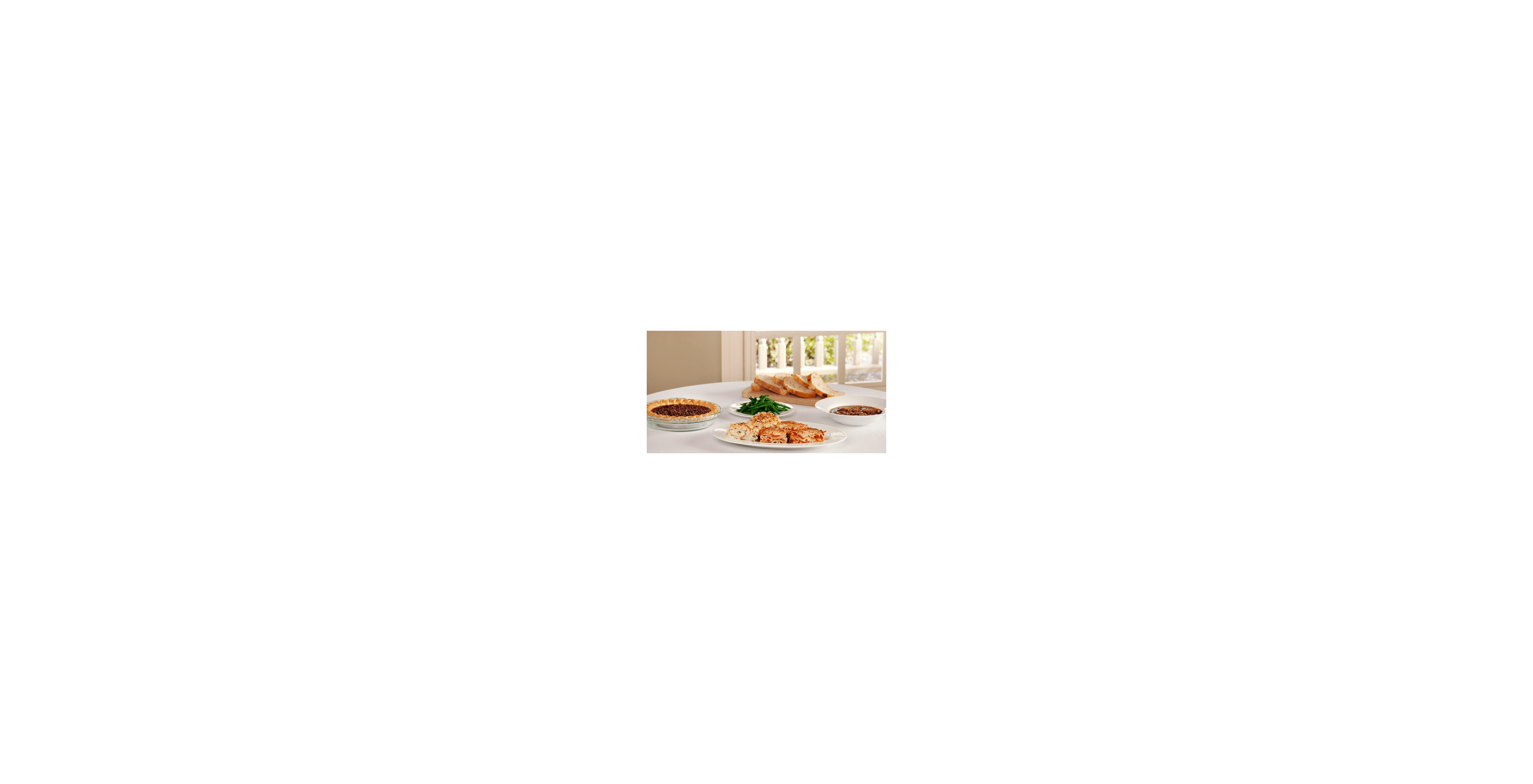 A beautifully arranged meal includes savory dishes like pie, green beans, and freshly baked bread.