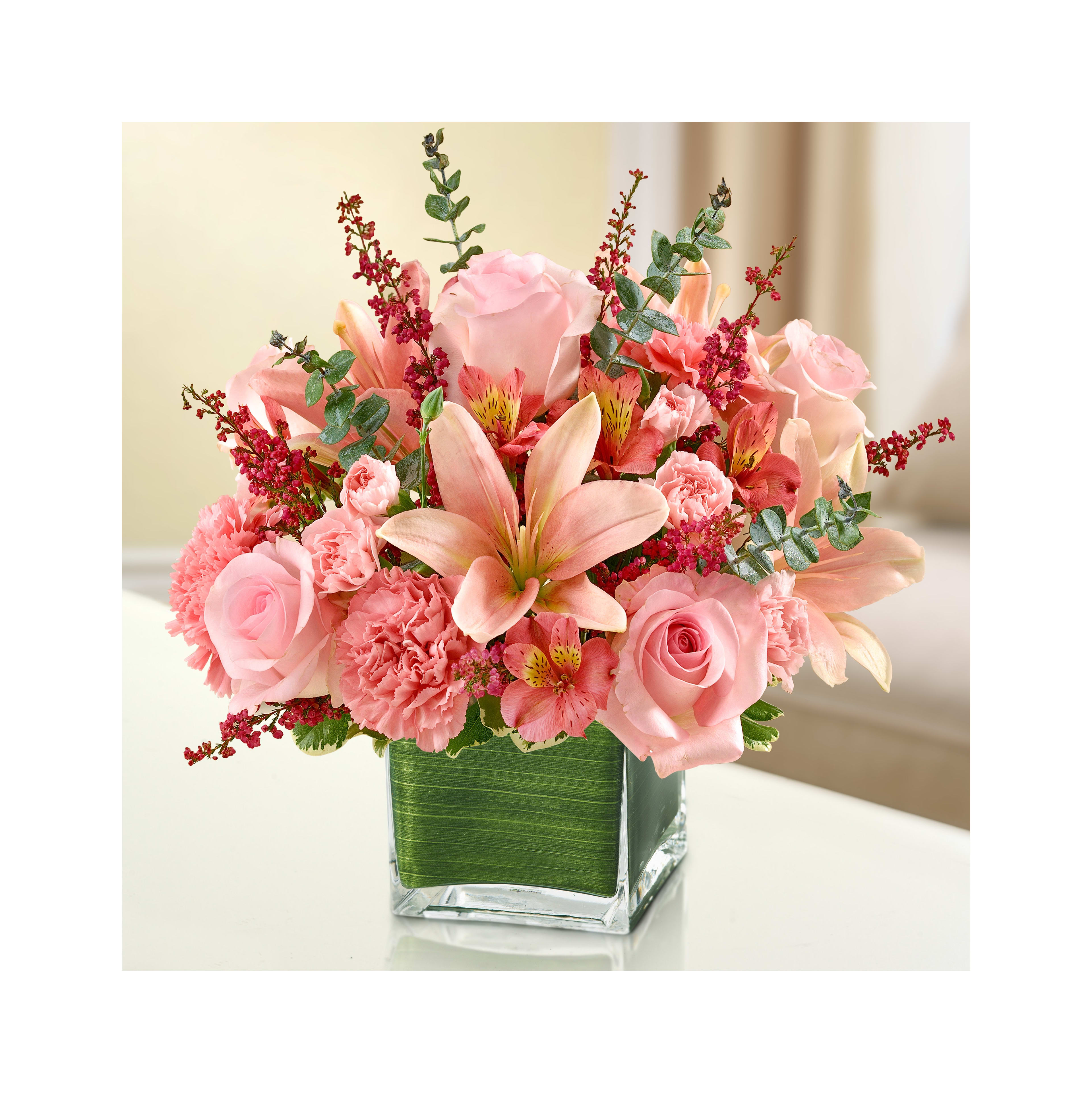 Beautiful pink roses, lilies, and greenery create an uplifting centerpiece for a cozy space.